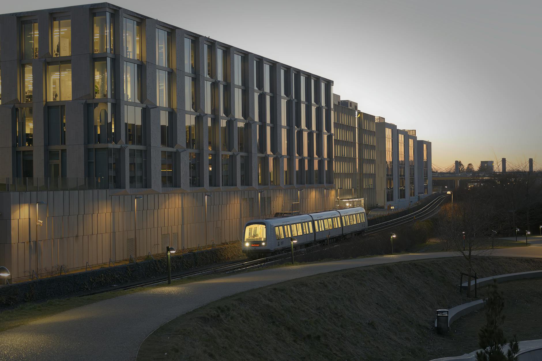 Modern urban train moving through Frederiksberg at dusk.