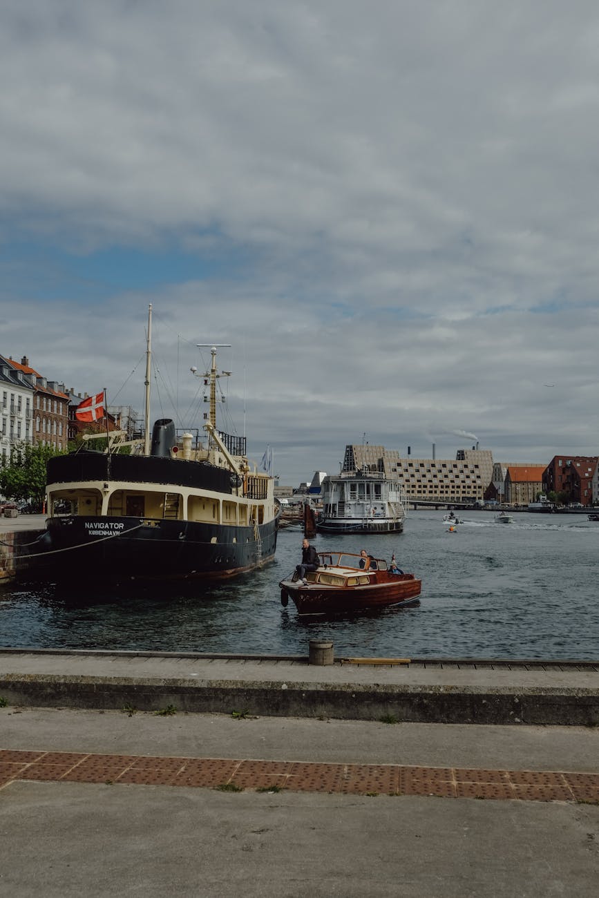 Boats docked in Copenhagen harbor under a cloudy sky.