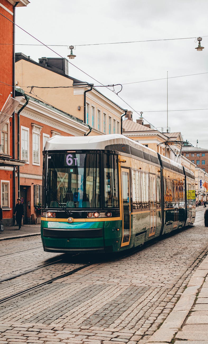 Green tram moving through a Helsinki street.