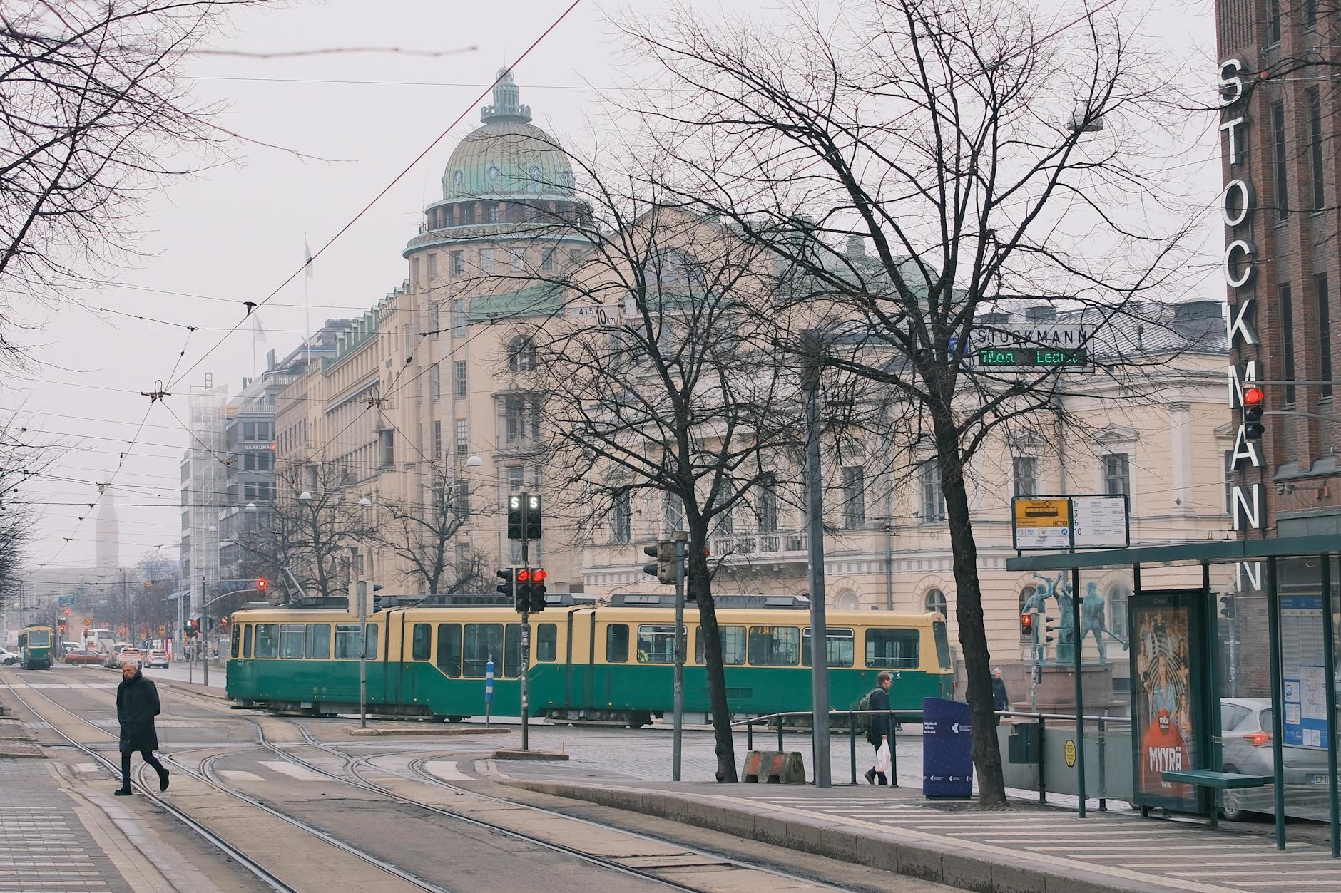 Street scene in Helsinki with tram tracks and central shopping district signage.