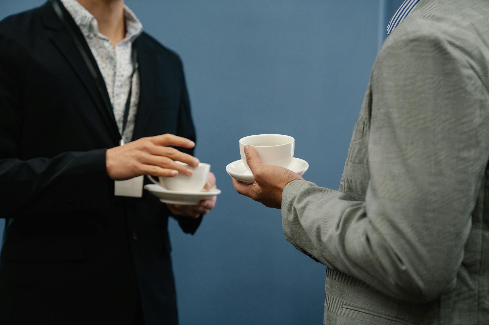 Two business professionals holding coffee cups during a casual meeting or event.