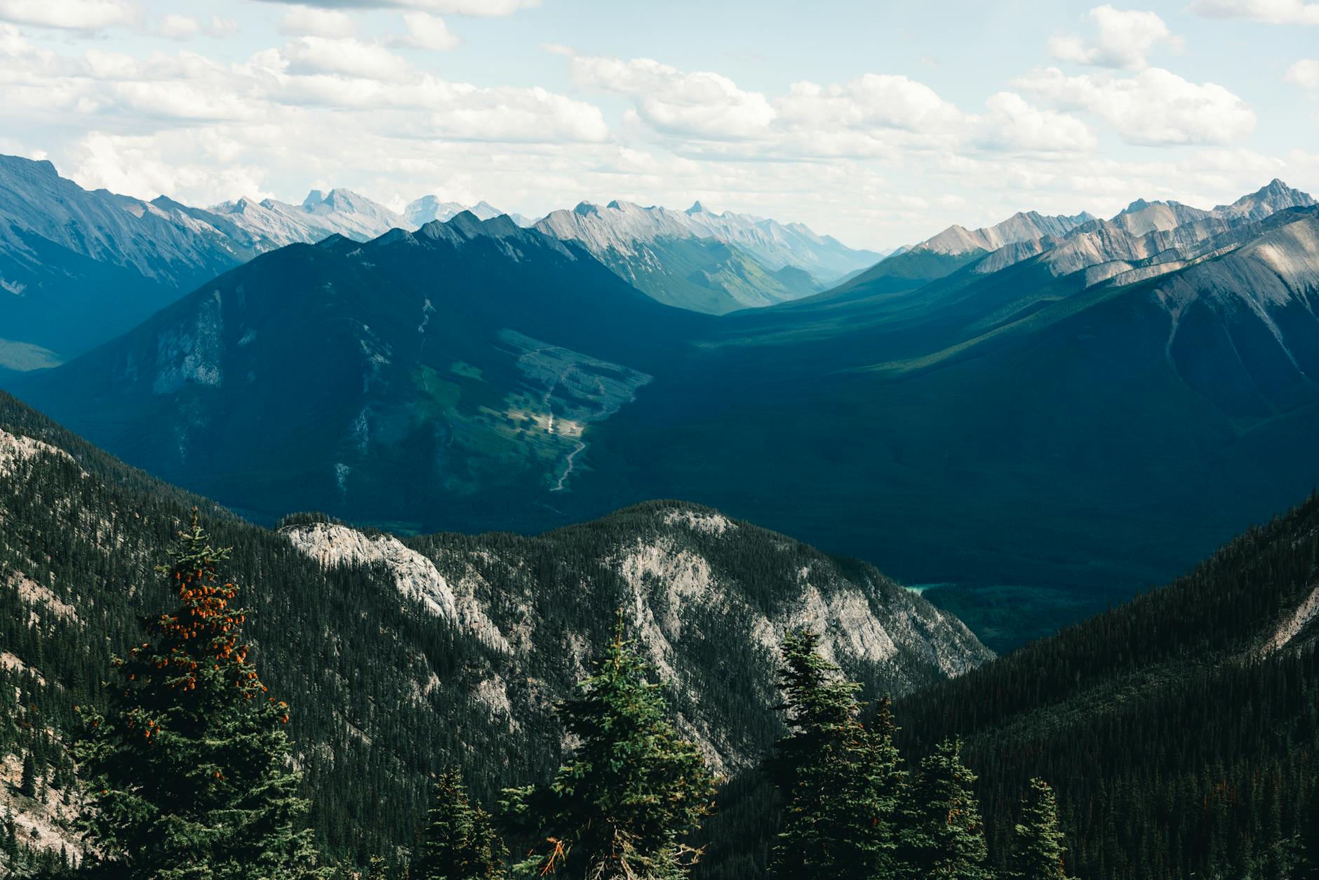 Stunning panoramic view of the Canadian Rockies in Banff National Park, showcasing lush valleys and steep peaks.