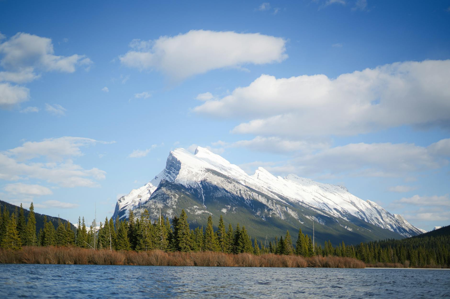 A breathtaking view of snow-capped mountains by Vermilion Lakes in Banff National Park.