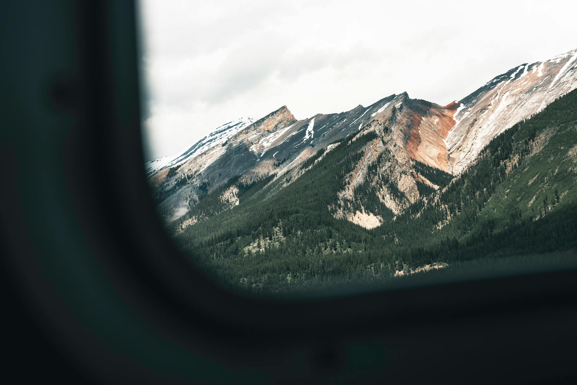 Breathtaking view of Banff's rugged mountains captured through an airplane window, showcasing natural beauty.