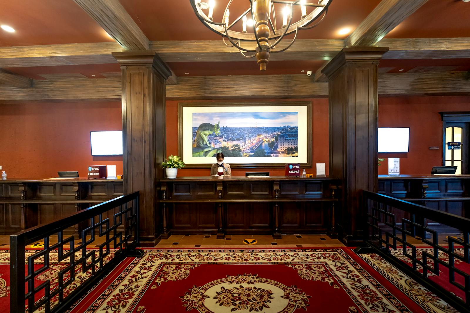 Elegant hotel lobby with receptionist at the front desk under warm lighting.