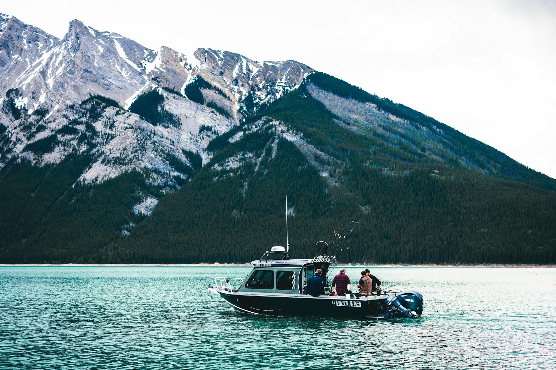 A boat with people enjoying a scenic ride on a lake in Banff National Park, surrounded by mountains.
