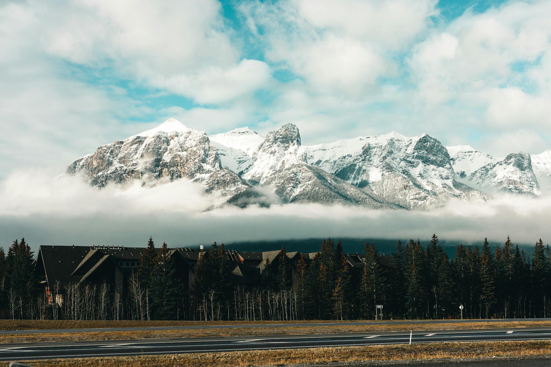 Stunning view of snow-capped mountains in Canmore, Alberta, with a forest and cabins.