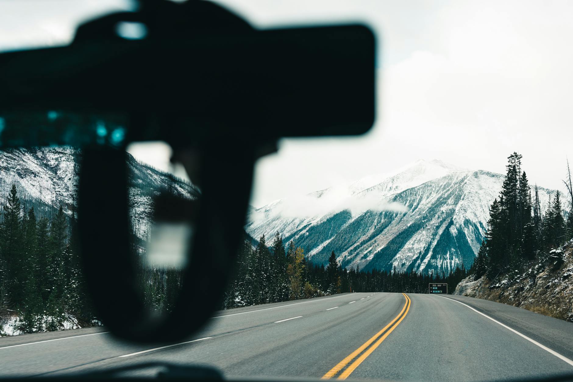 Capture of a snowy mountain highway in Banff National Park from a vehicle perspective.