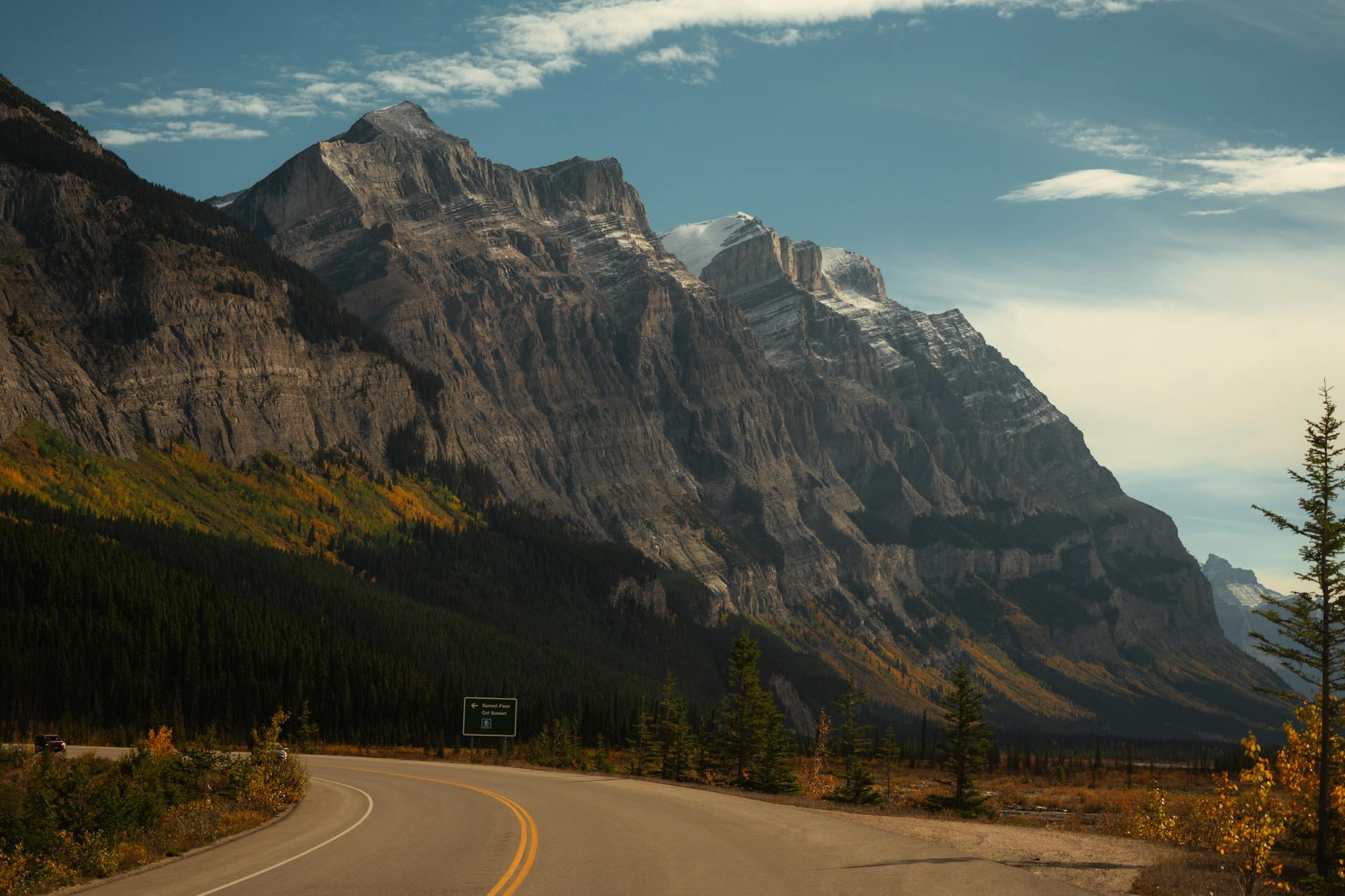 A winding road through a majestic mountain landscape during autumn.