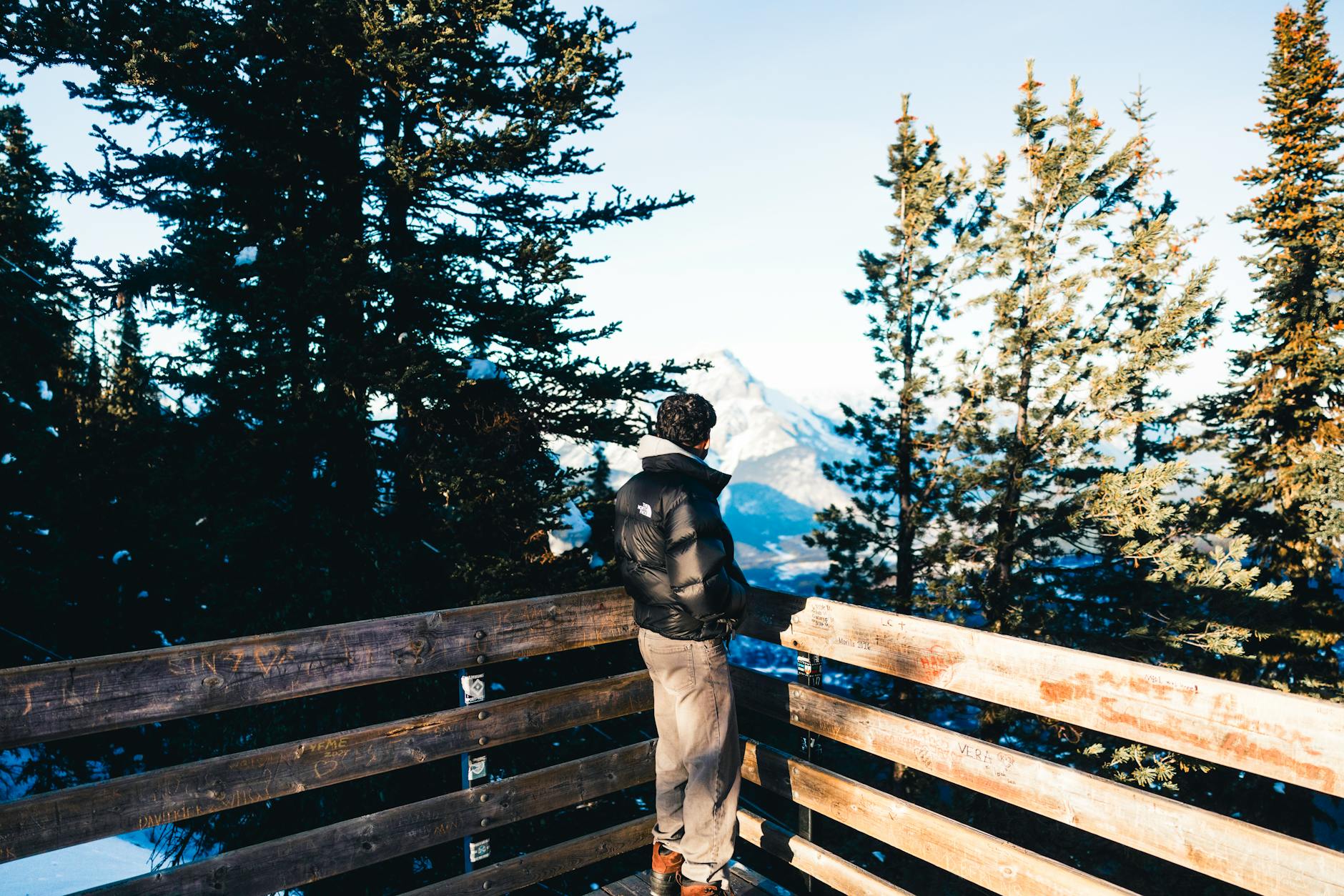 A person enjoys the scenic mountain view from a wooden lookout in Banff National Park.