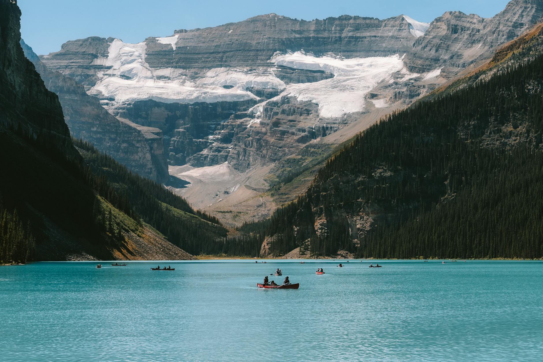 Canoes on tranquil Lake Louise with stunning mountain backdrop, perfect for adventure travel.