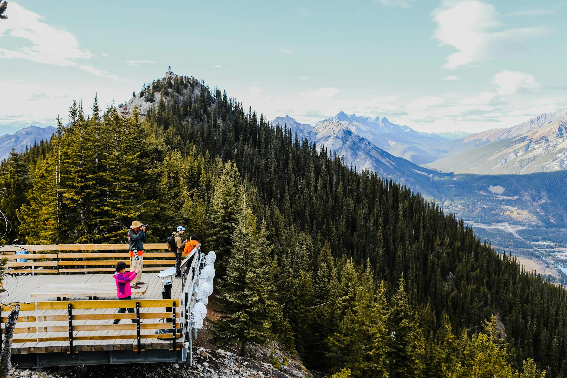 Tourists enjoying the stunning view from a mountain observation deck in Canada.