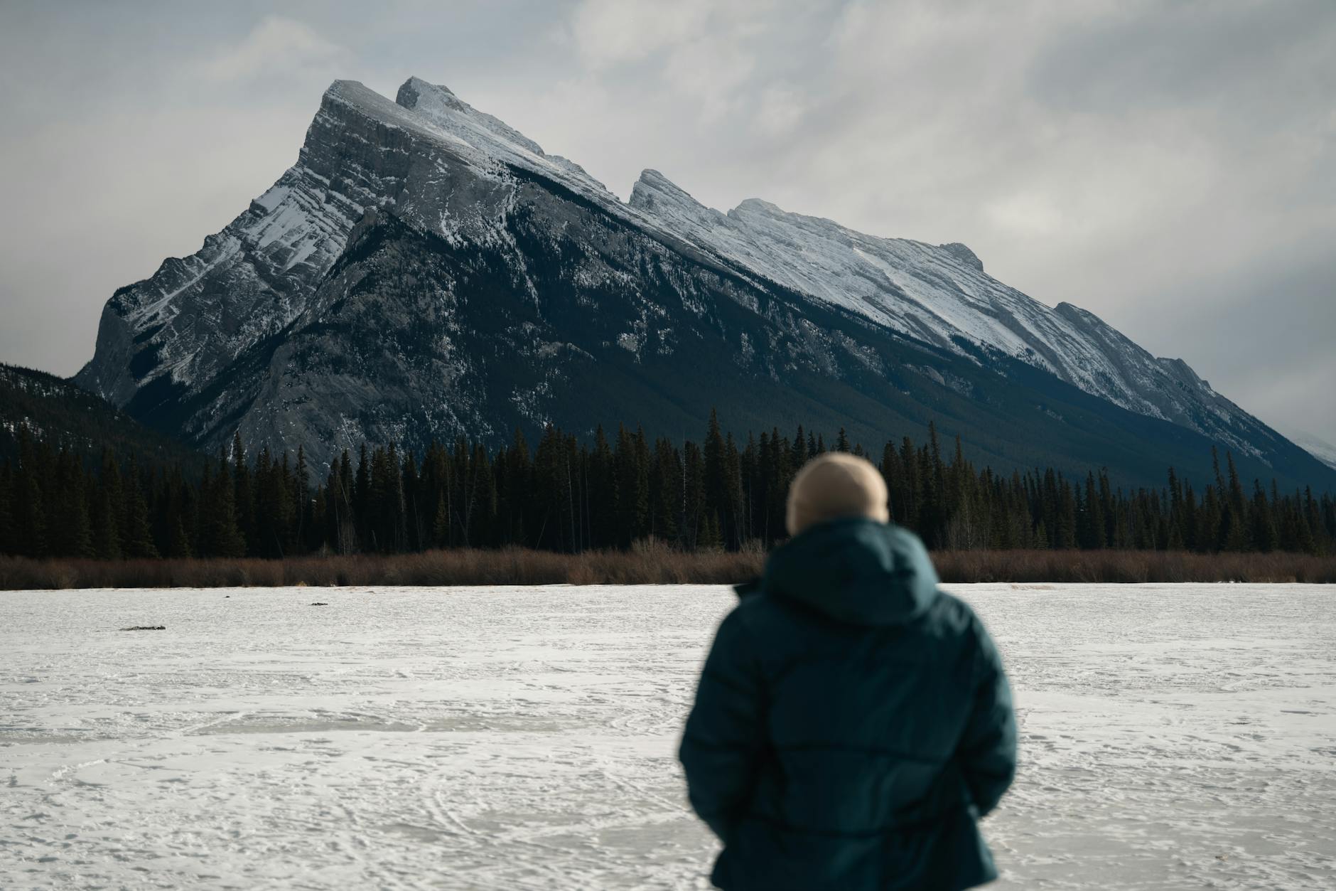 A person views the snow-covered Mount Rundle in Banff, Canada, during winter.
