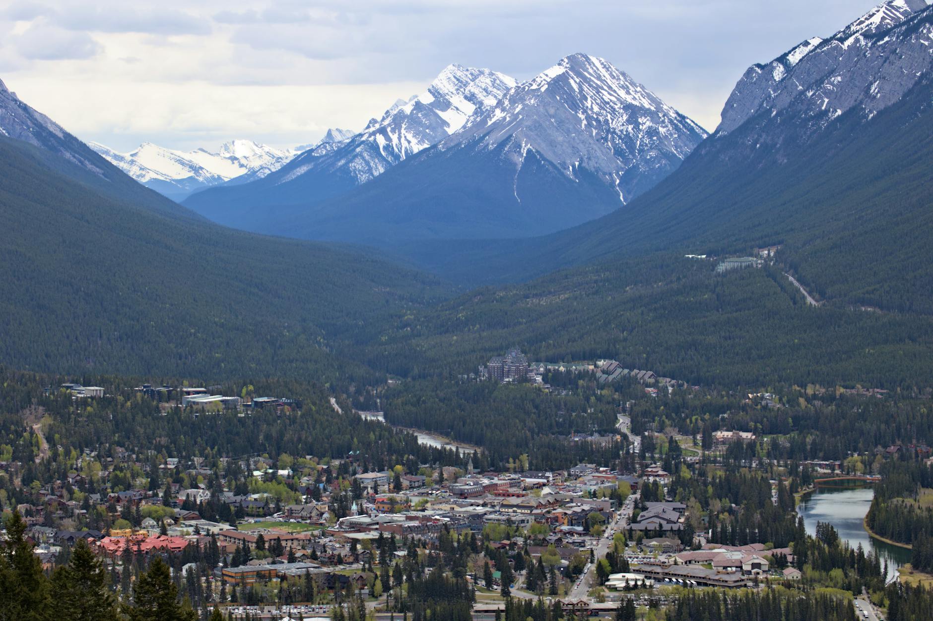 A breathtaking aerial view of Banff, AB, Canada showcasing majestic snow-capped mountains and lush greenery.
