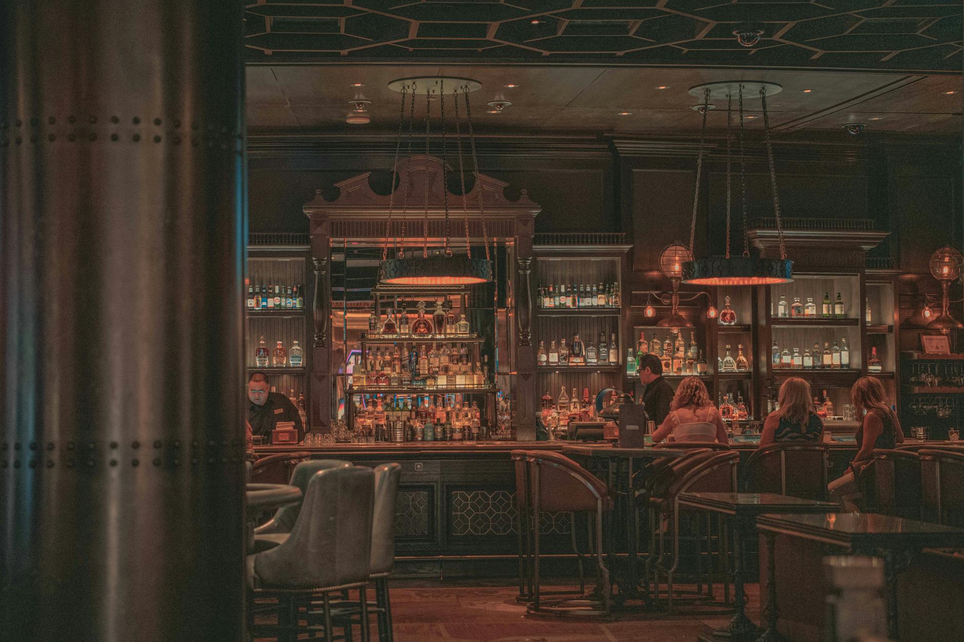 Warm and inviting bar scene with patrons enjoying drinks amidst vintage decor and ambient lighting.