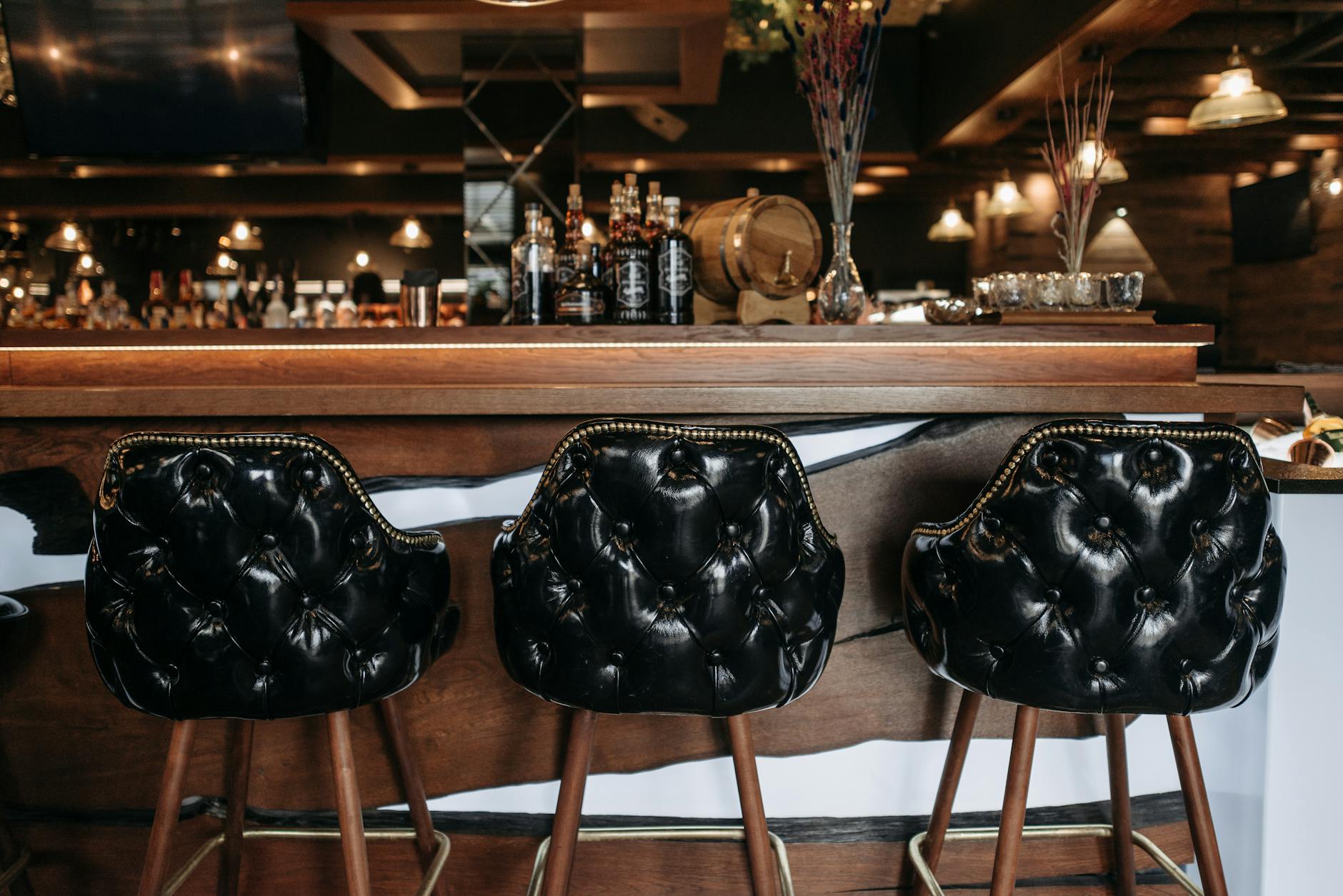 Sophisticated bar interior featuring luxurious leather stools and a stylish wooden counter.