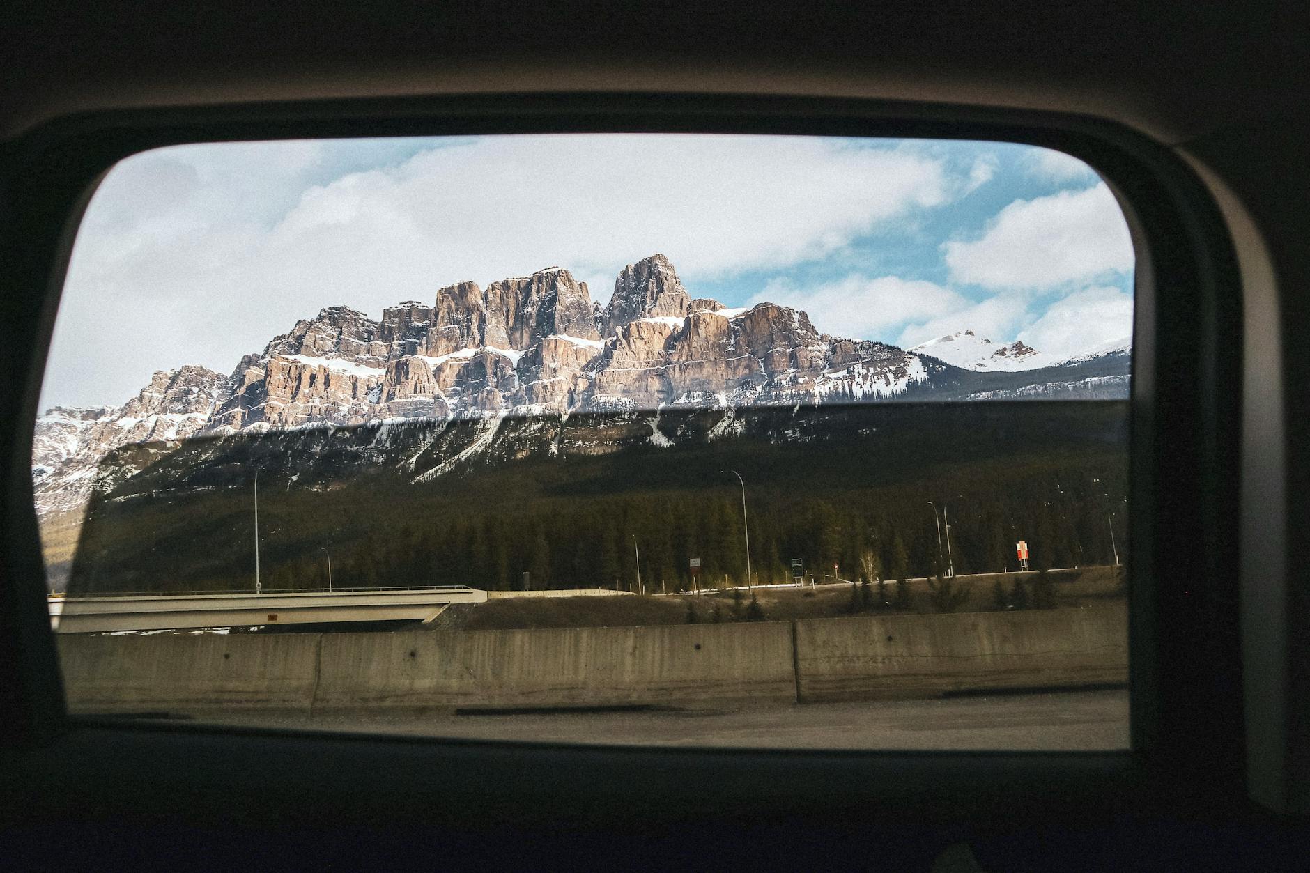 A breathtaking view of Castle Mountain in Banff National Park through a car window on a winter day.