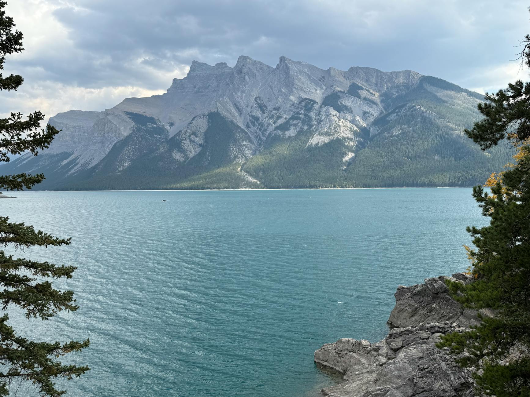 Breathtaking view of a turquoise lake framed by majestic mountains and lush forest.