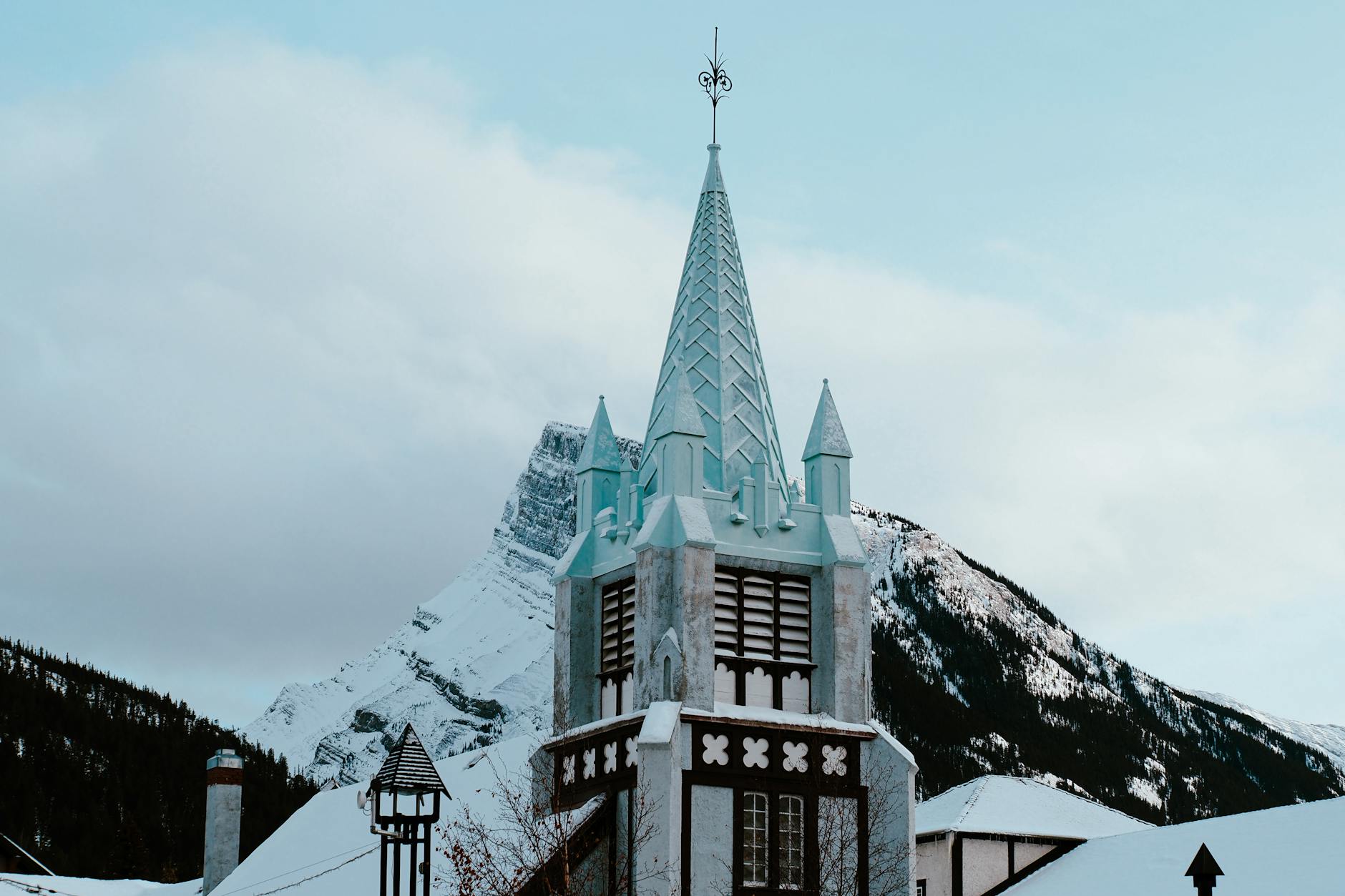 Idyllic view of a snowy church steeple against the mountain backdrop in Banff, Canada.