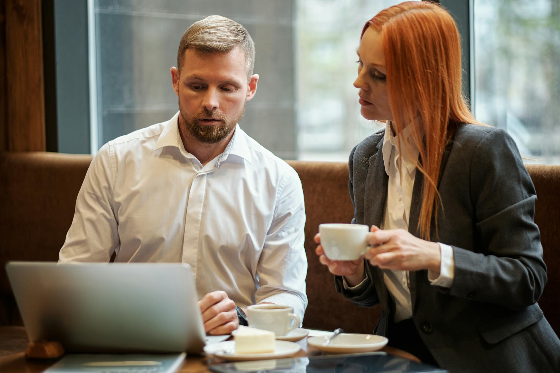 Two professionals discuss work over coffee in a modern cafe.