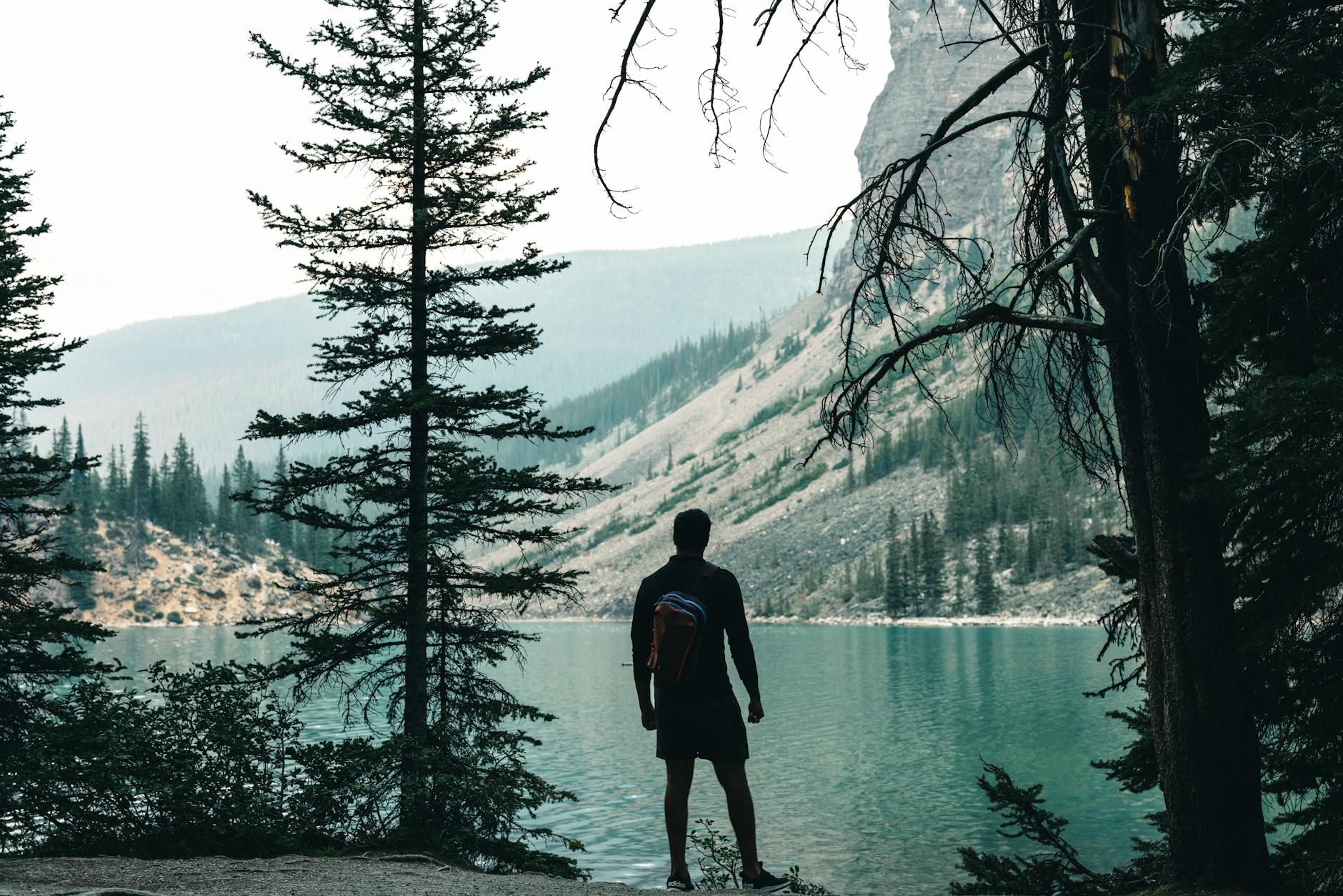 Silhouette of a hiker overlooking the turquoise waters of Moraine Lake in Banff, Canada.