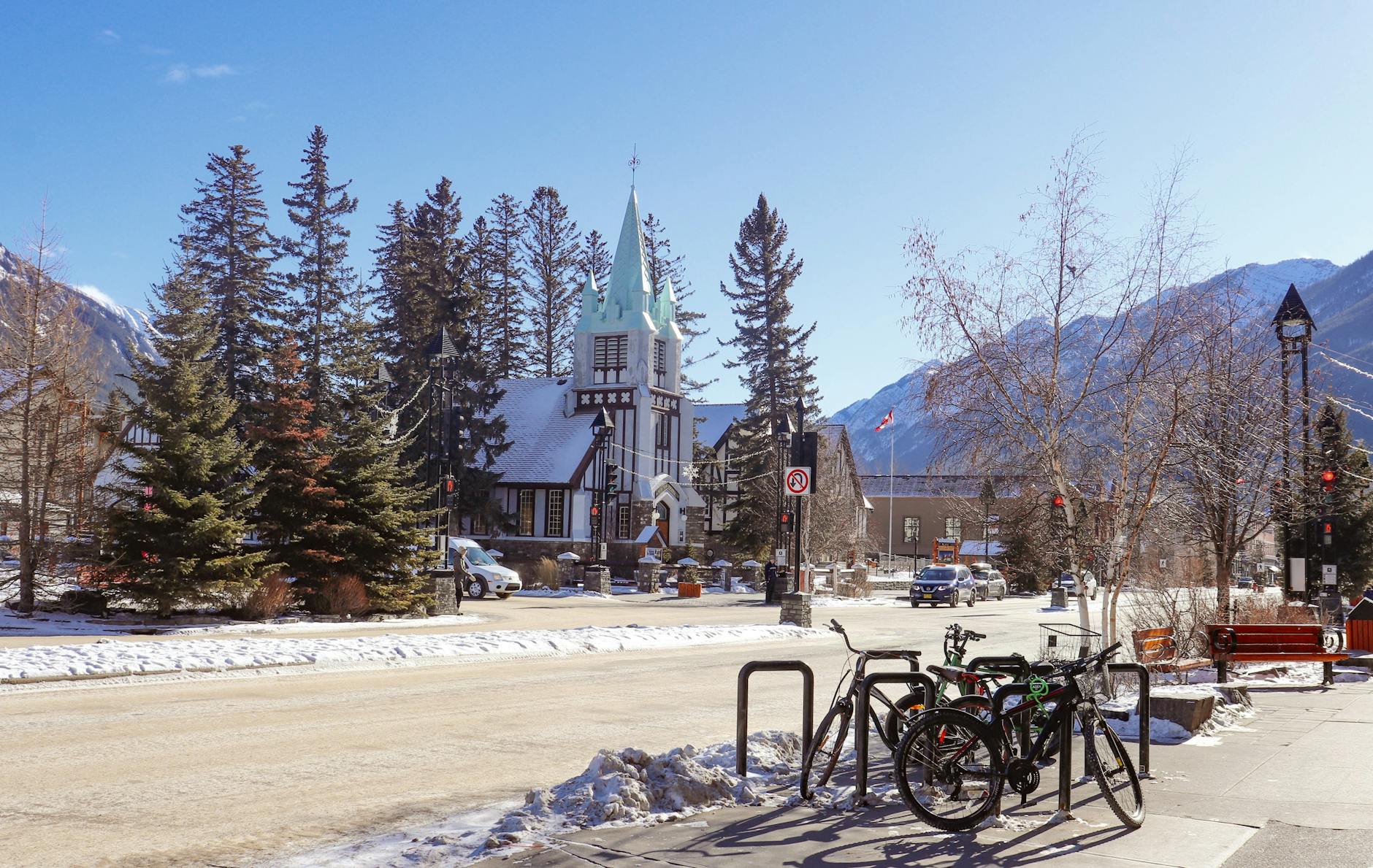 Scenic winter street view in Banff, Alberta with snow, bicycles, and mountains.