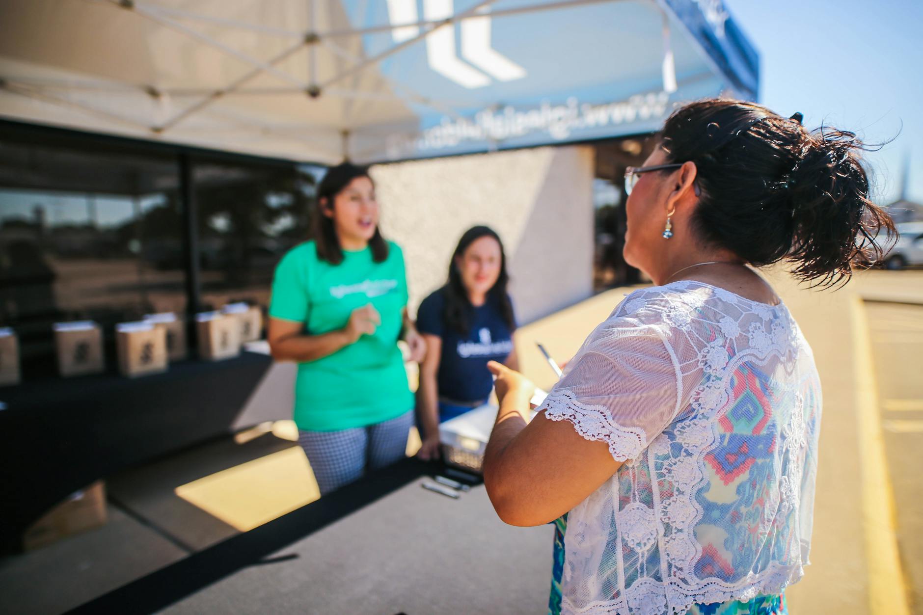 People engaging at an outdoor community event registration booth, creating a lively atmosphere.