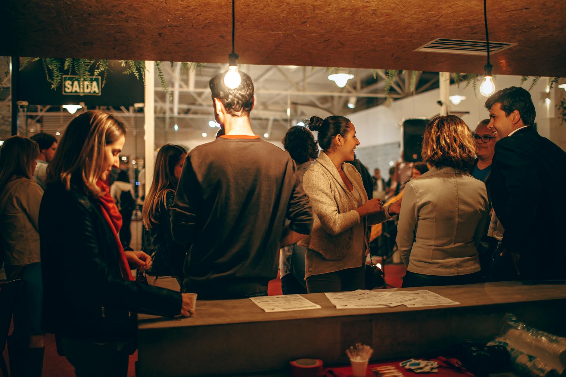 A lively indoor social gathering with people interacting warmly under cozy lighting.