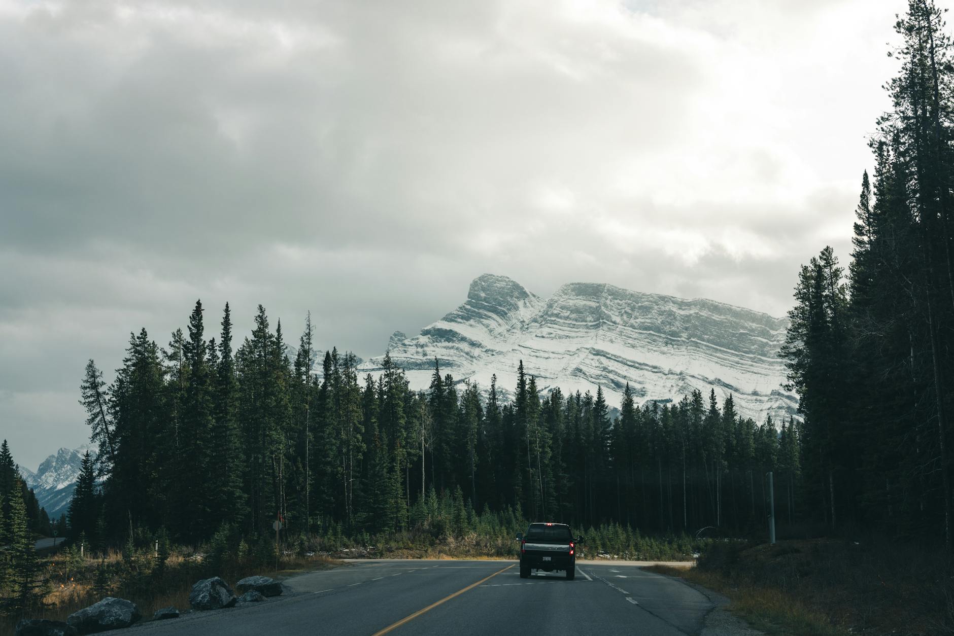 A picturesque road trip scene through Banff National Park, showcasing majestic mountains and lush forests.