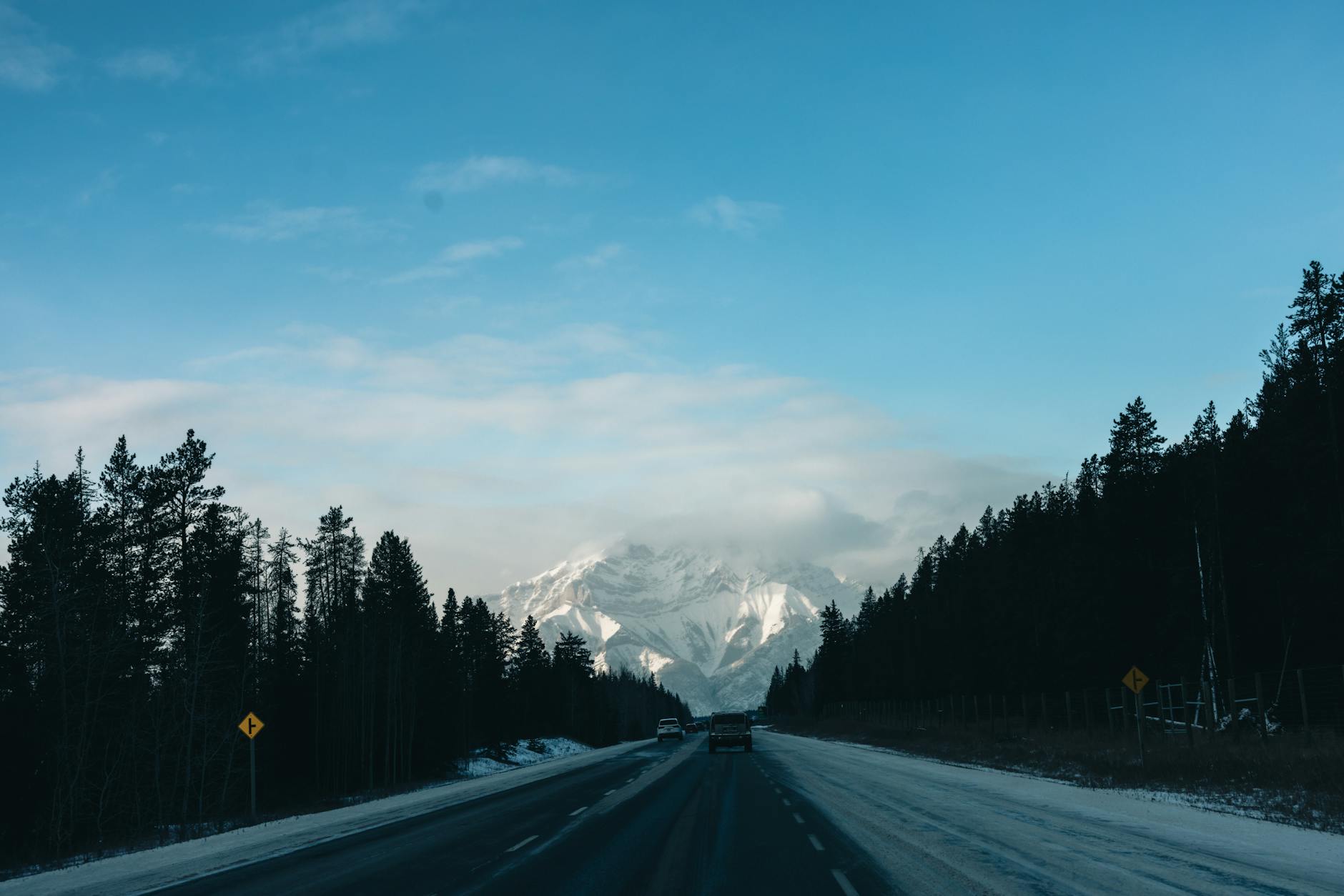 Winter road trip through Banff National Park with snow-covered mountains and pine trees.