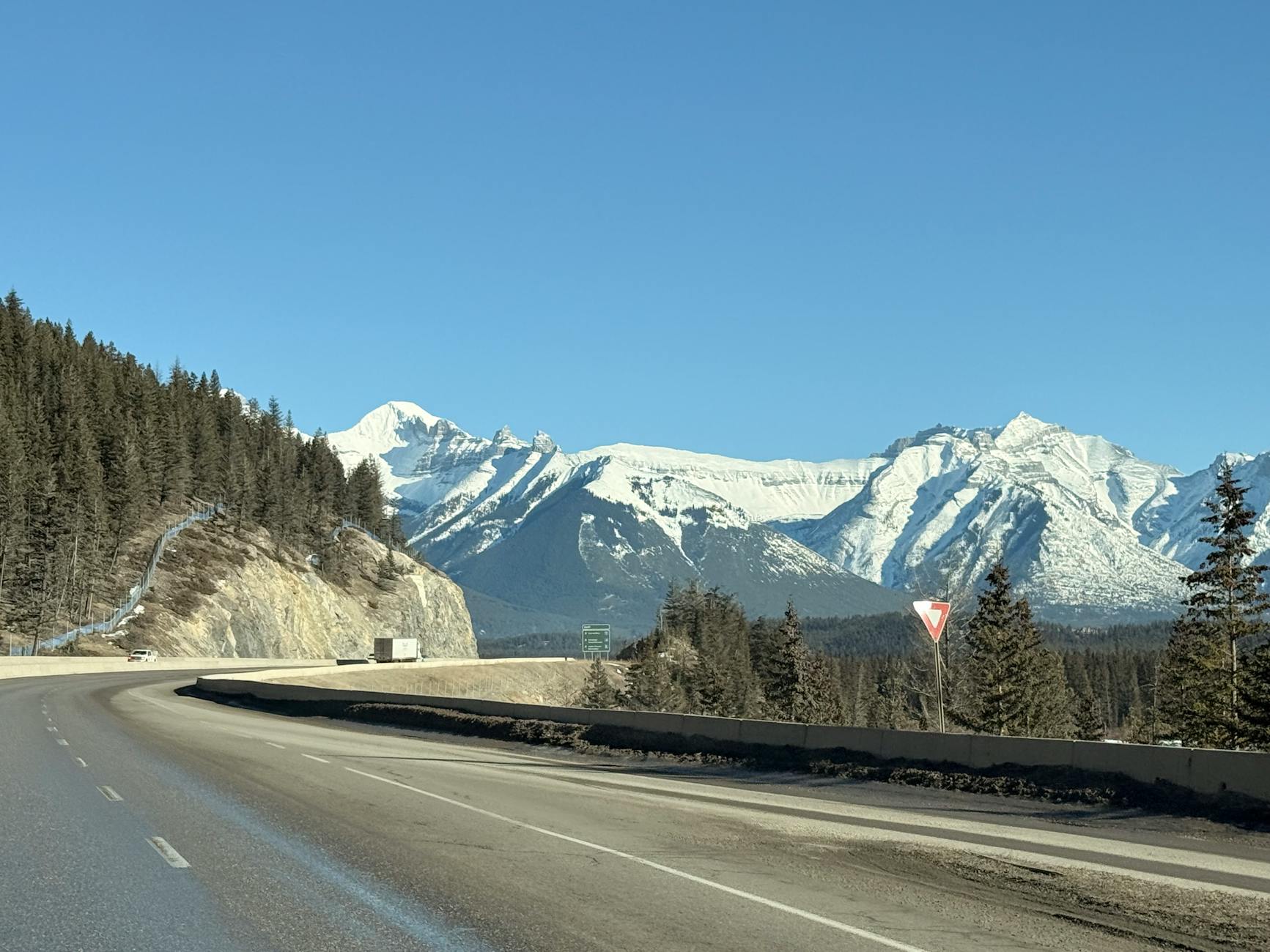 A picturesque winter highway in Banff with snow-capped mountains and clear blue skies.