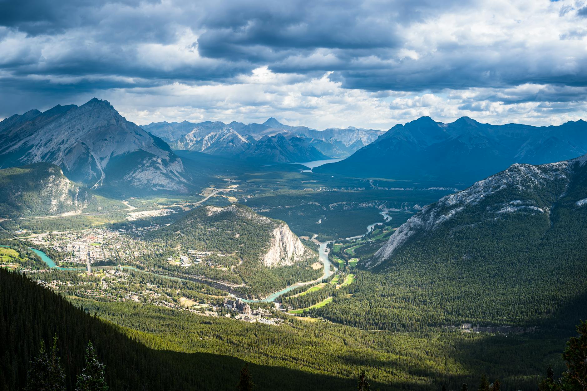 Scenic vista of cloud-covered mountain peaks and lush valleys in Banff National Park.