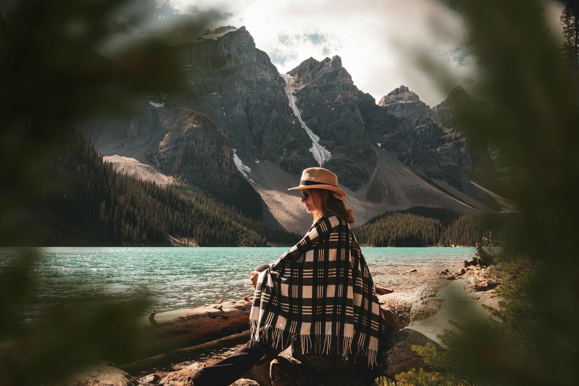 Woman enjoying a peaceful moment by Moraine Lake with scenic mountain views in Alberta, Canada.