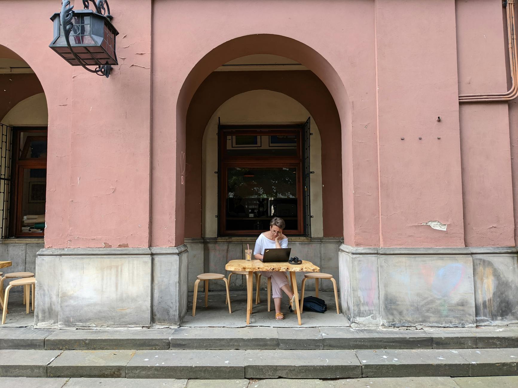 Consultant working on a laptop outside a cafe for quiet work planning.