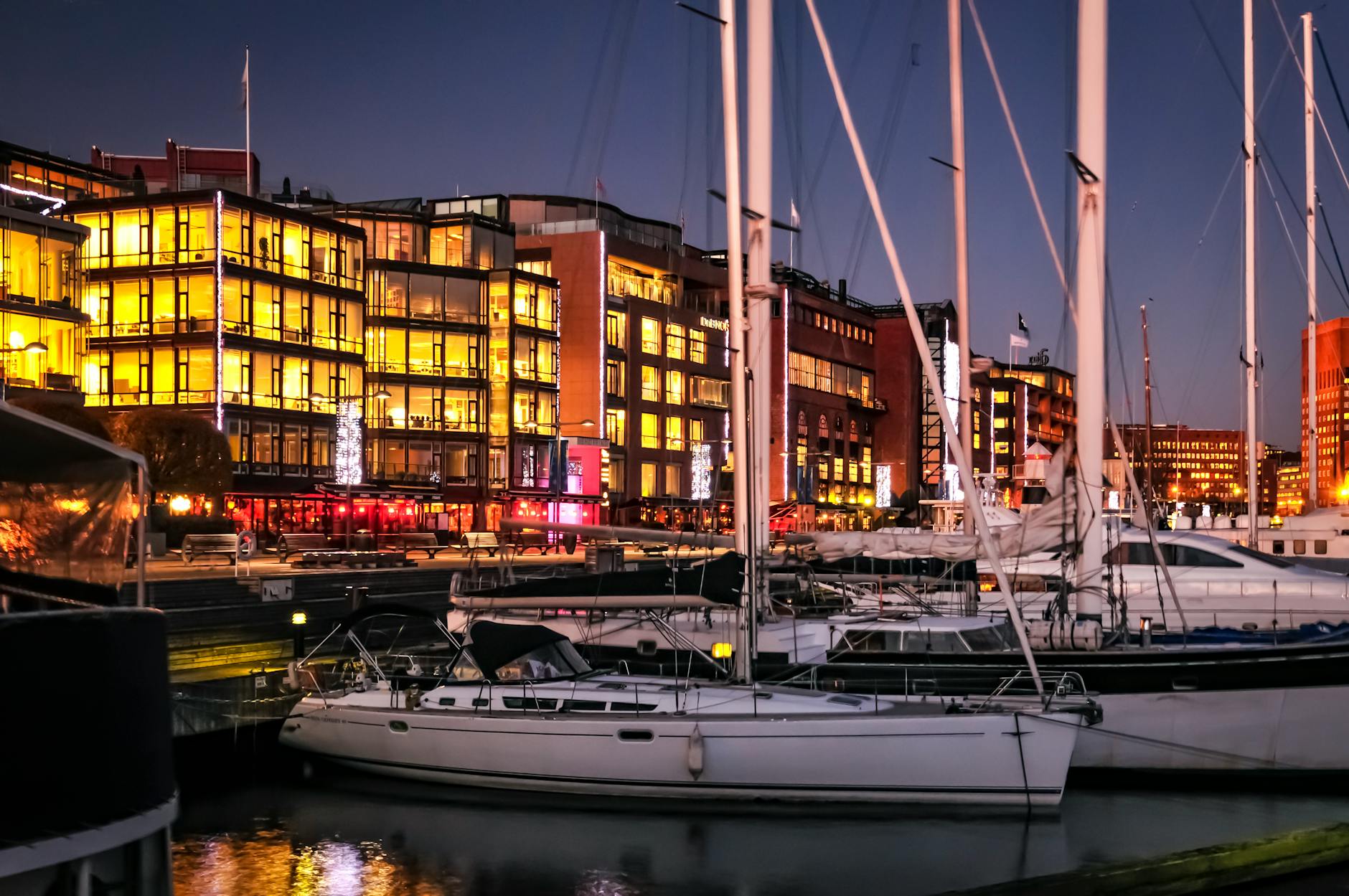 Harbor with yachts and glowing buildings for nightlife planning.