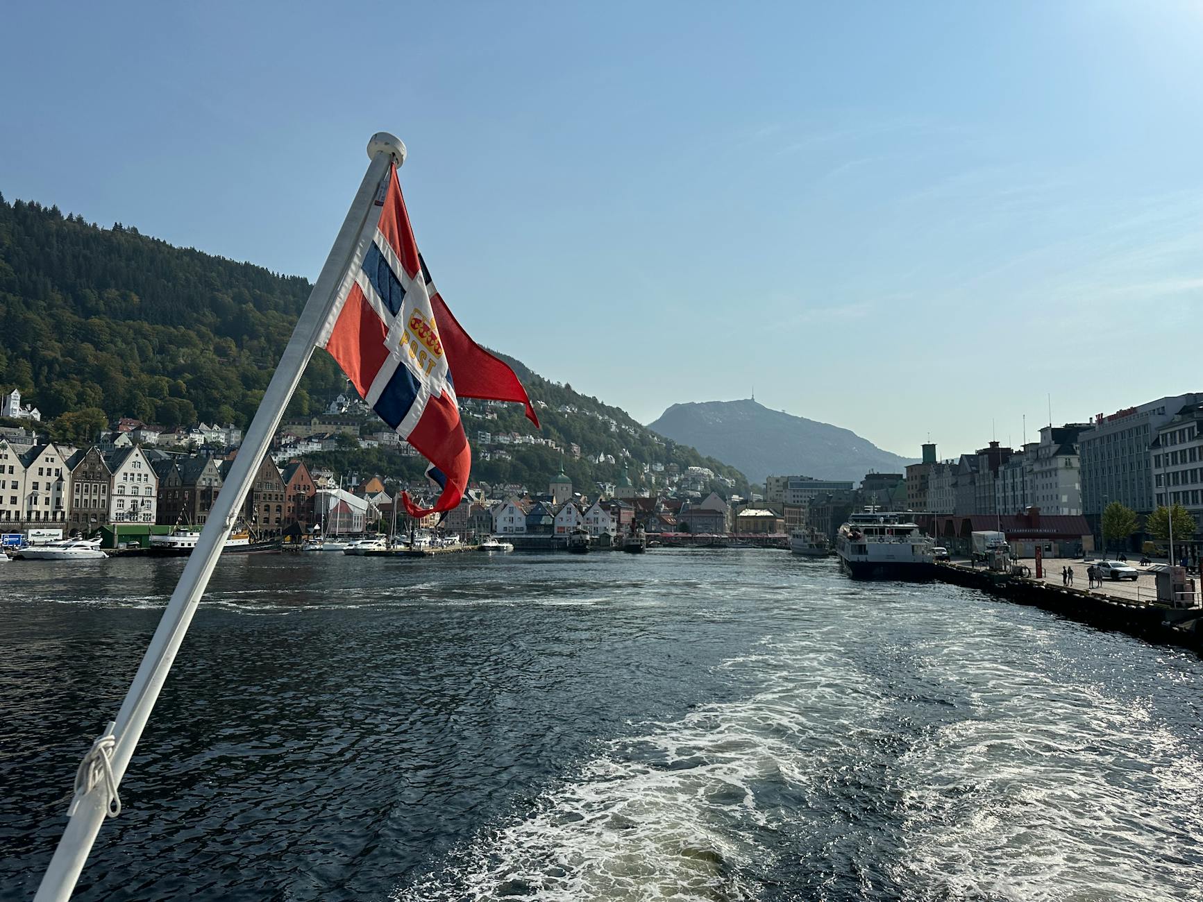 Norwegian flag over Bergen harbor for sales traveler planning.