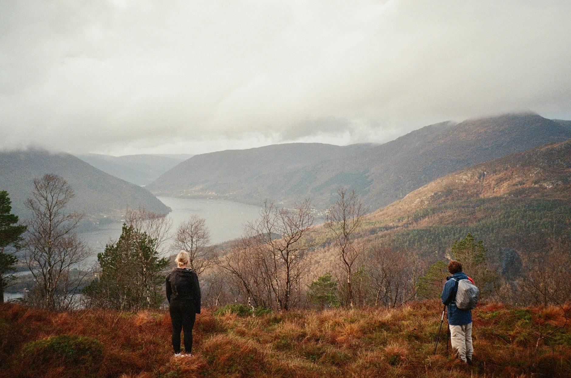 Hikers overlooking Bergen-area fjord scenery for solo viewpoint planning.