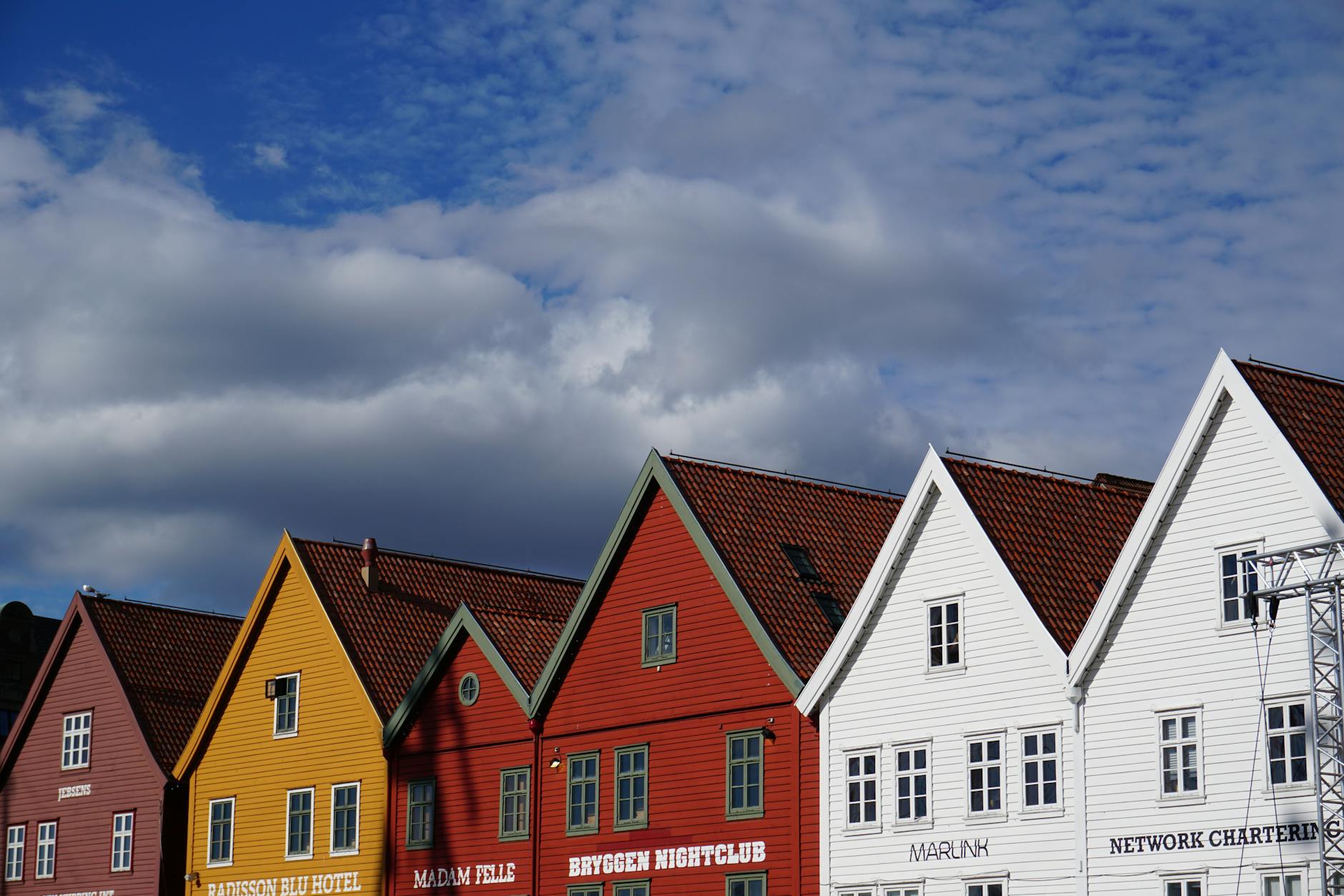 Colorful Bryggen buildings under blue sky for tourist planning.