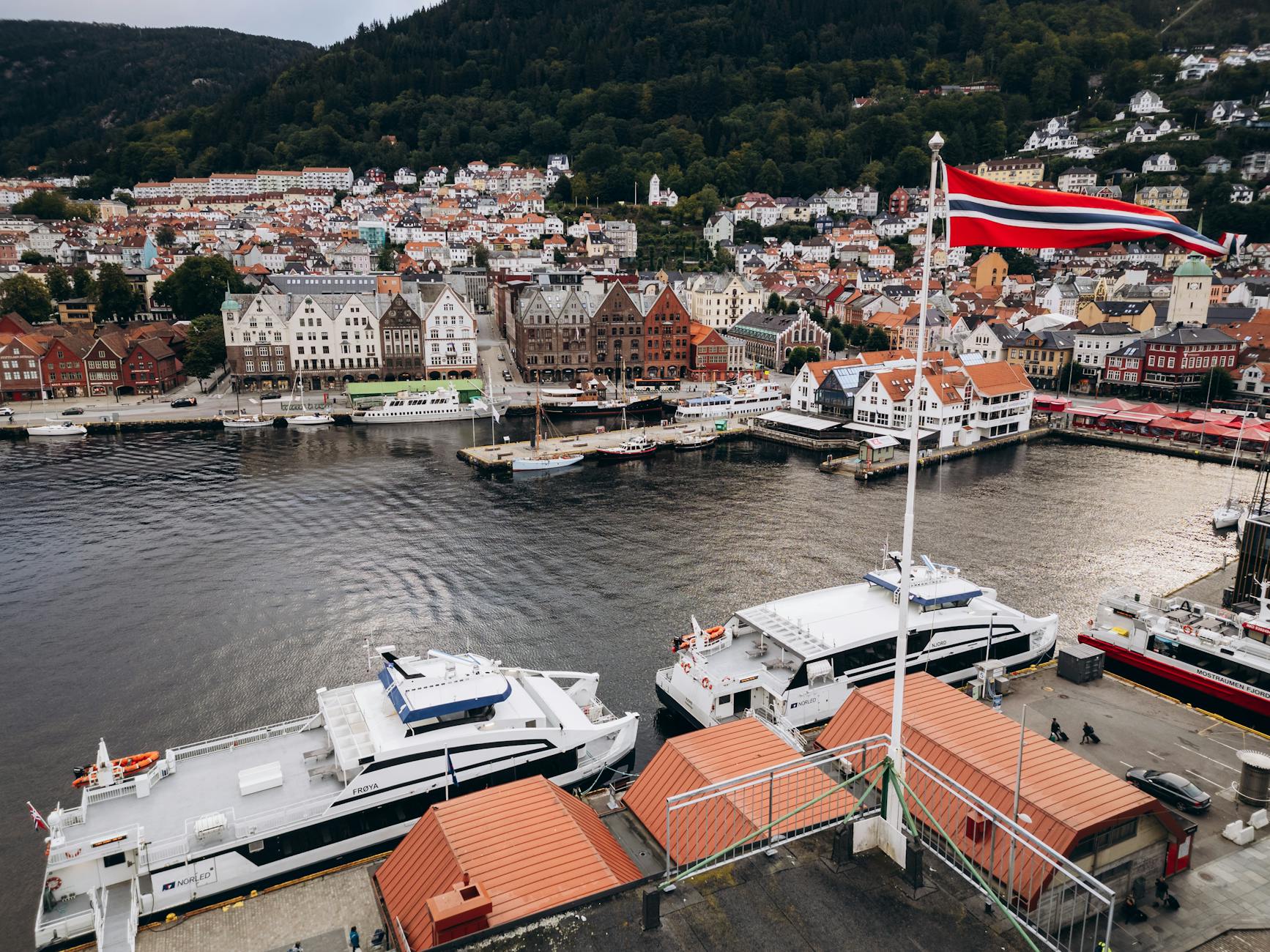 Aerial Bergen harbor with Norwegian flag for tourist viewpoint planning.