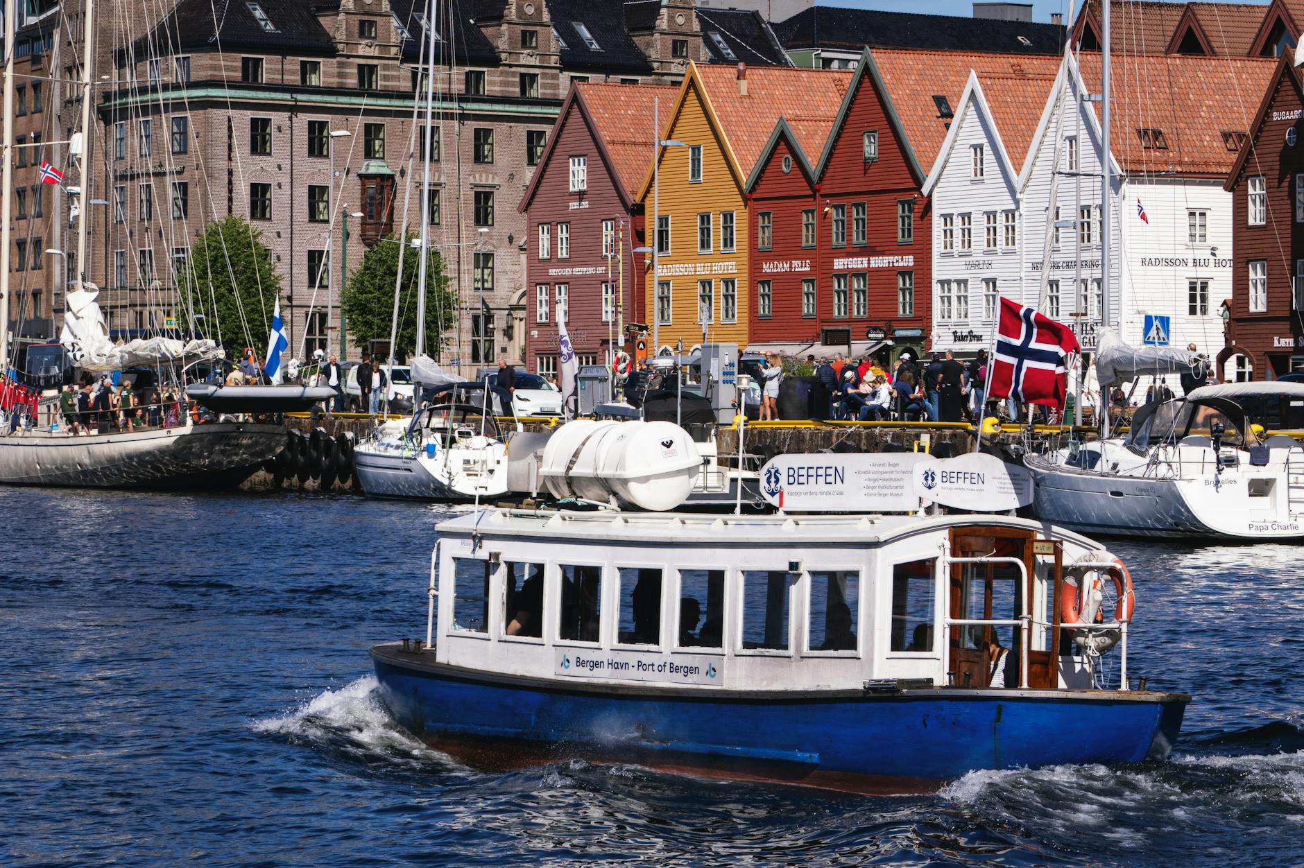 Bergen waterfront with boat and colorful buildings for tourist route planning.