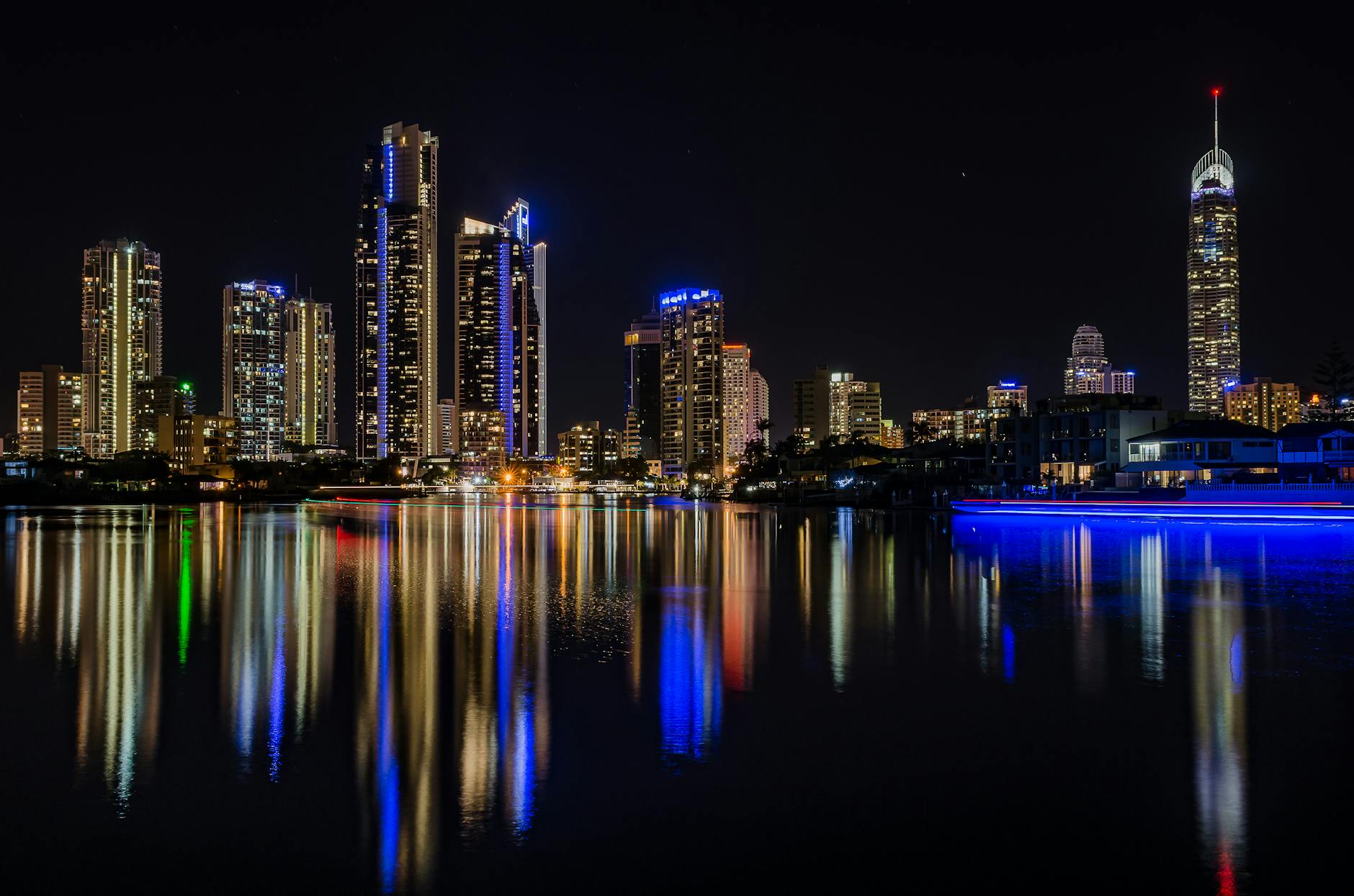Illuminated Queensland high-rises by the water for Brisbane late transport planning.