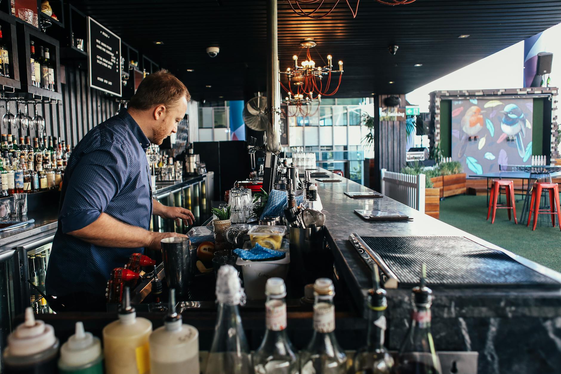 Bartender preparing cocktails at a rooftop bar for Brisbane nightlife travel report planning.