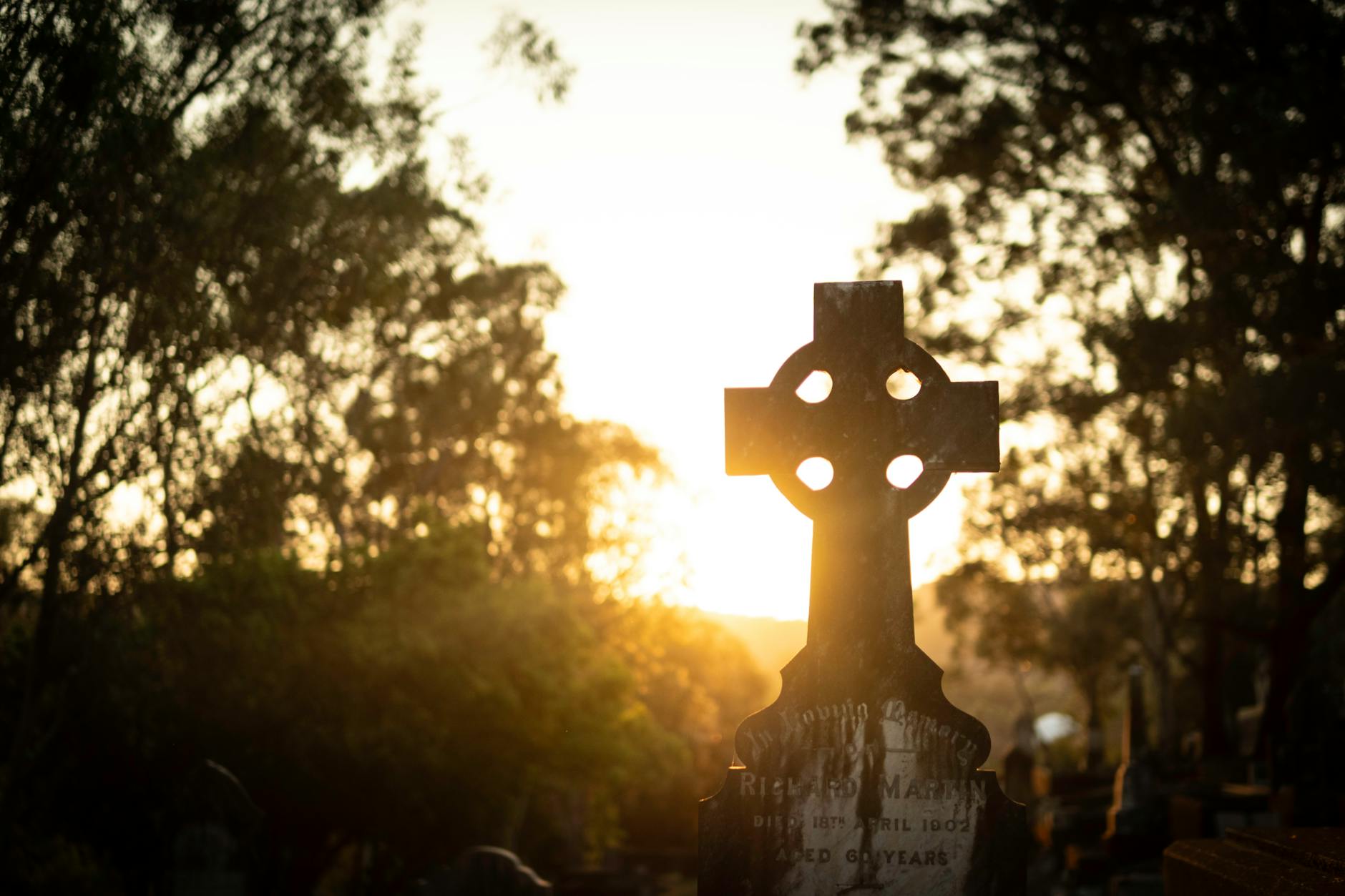 Celtic cross silhouette at Toowong Cemetery for Brisbane sacred-site route planning.