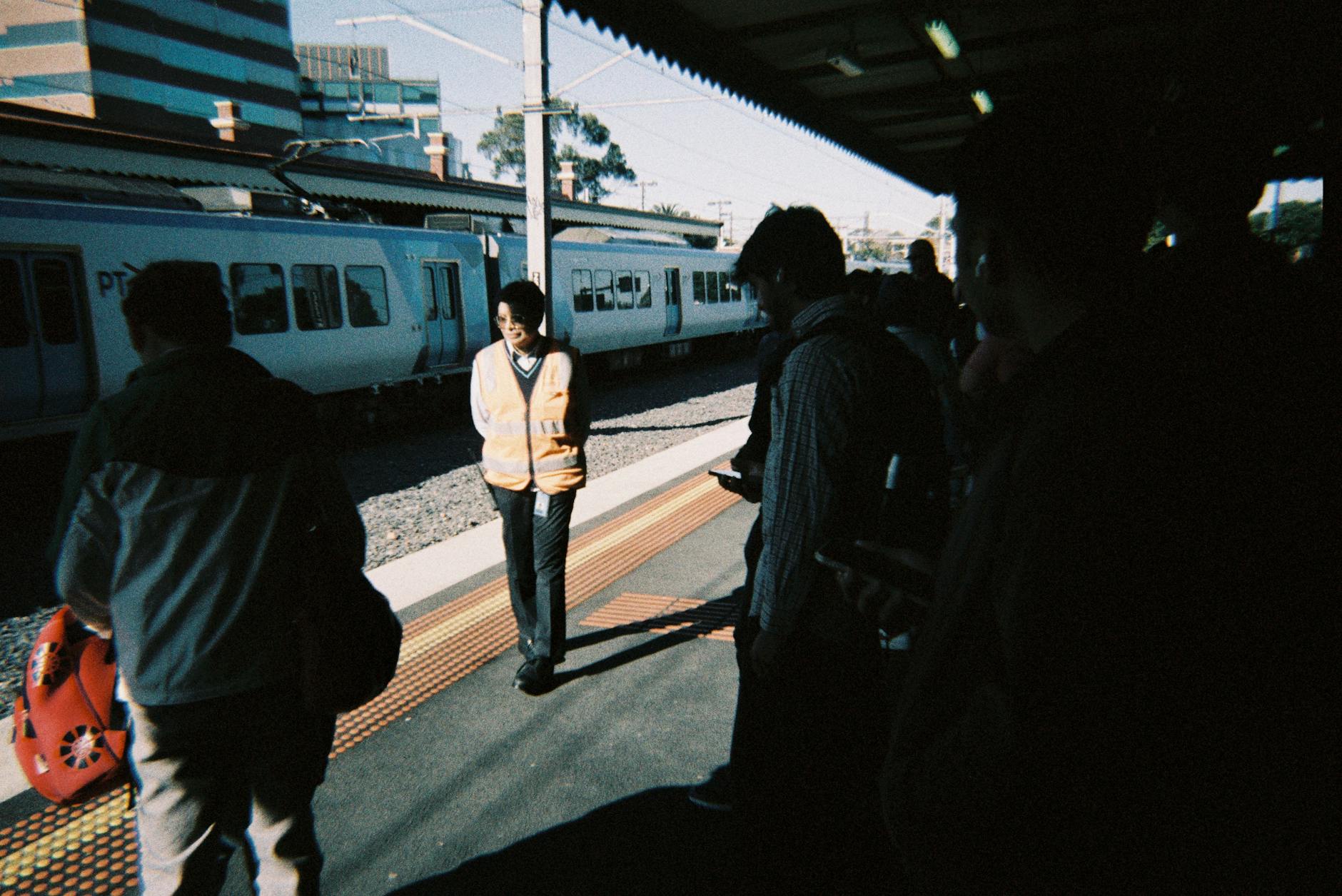 Commuters waiting at an Australian train station for Brisbane transit report planning.