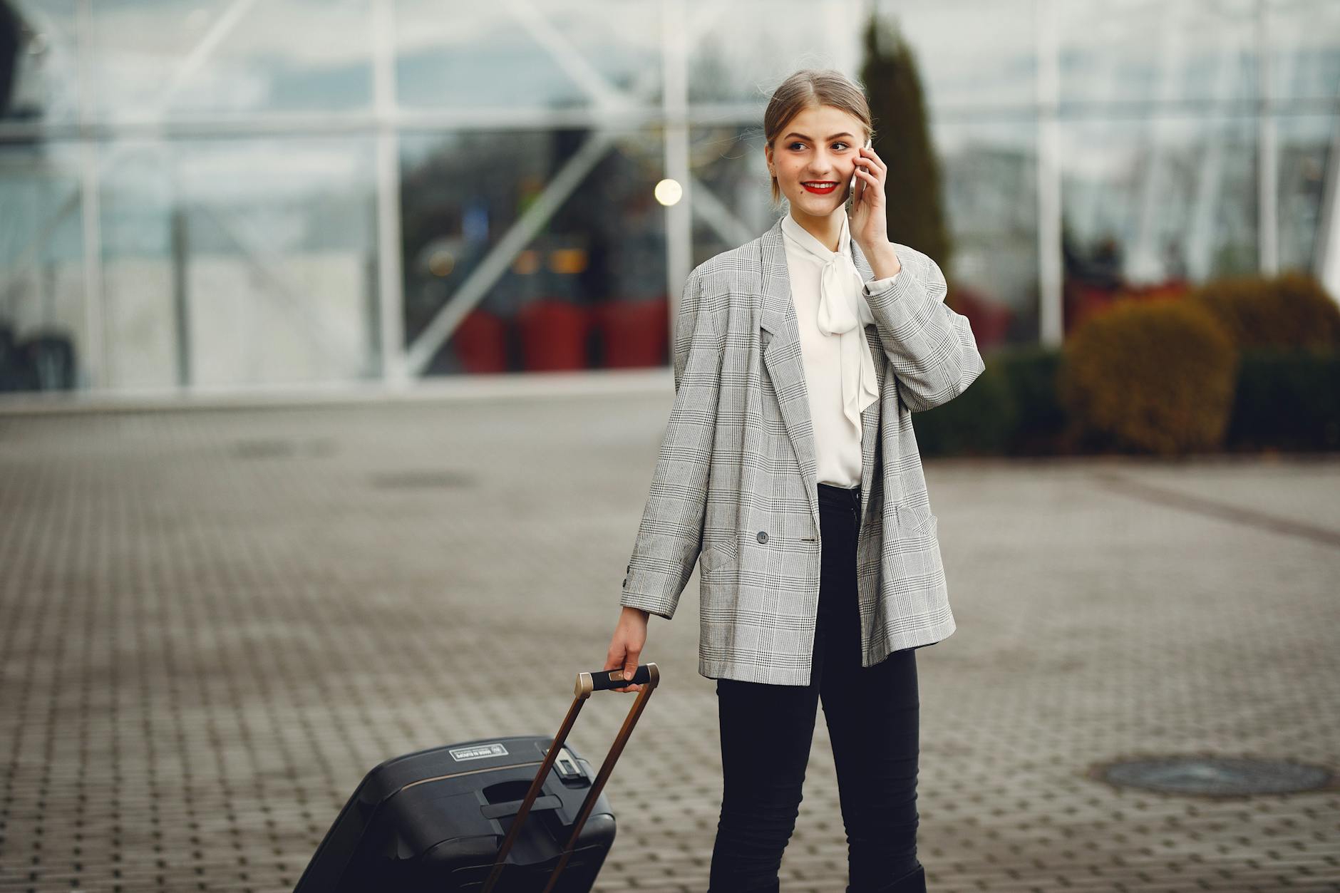 Business traveler with suitcase near an airport terminal for Brisbane transit work planning.