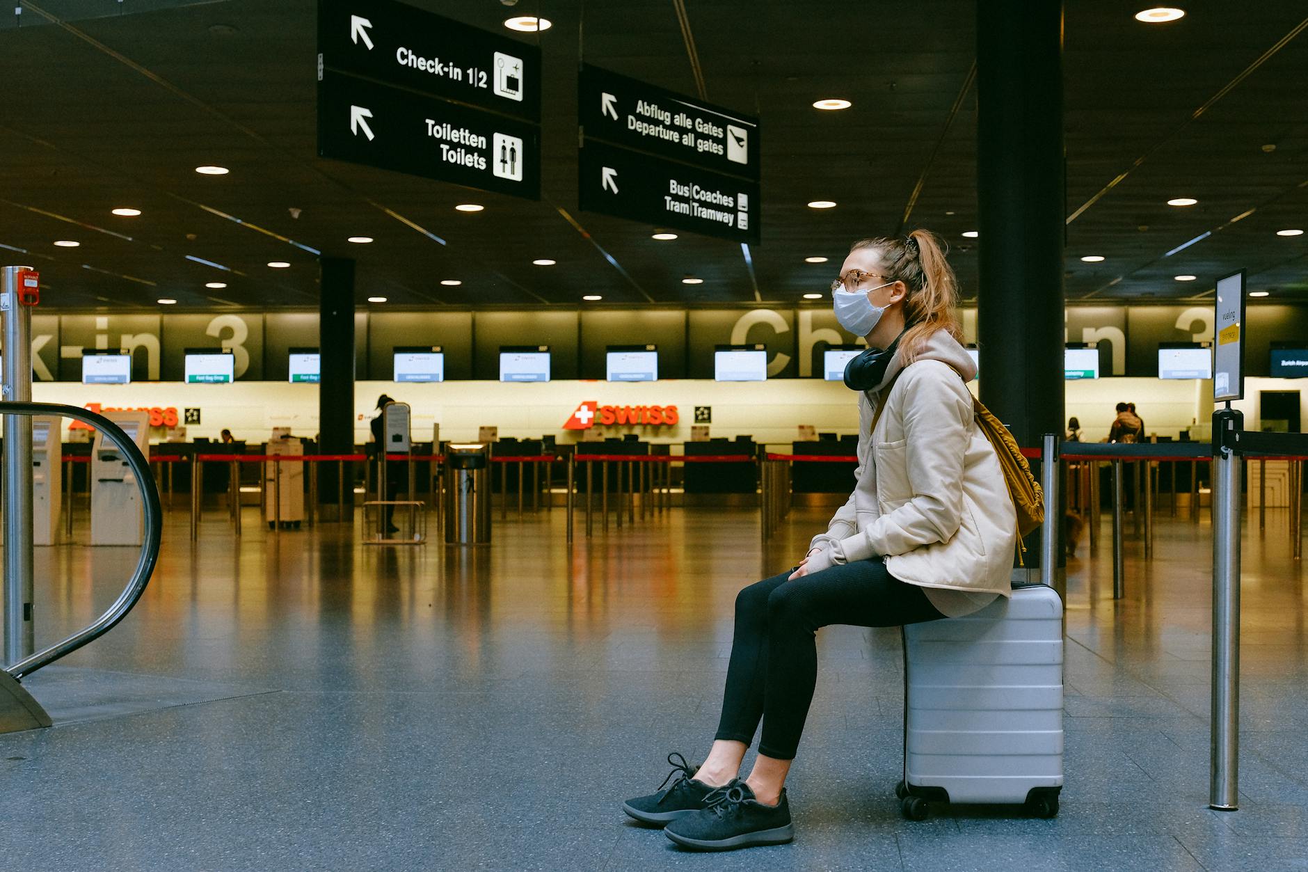 Traveler sitting on luggage in an airport terminal for Brisbane rest planning.