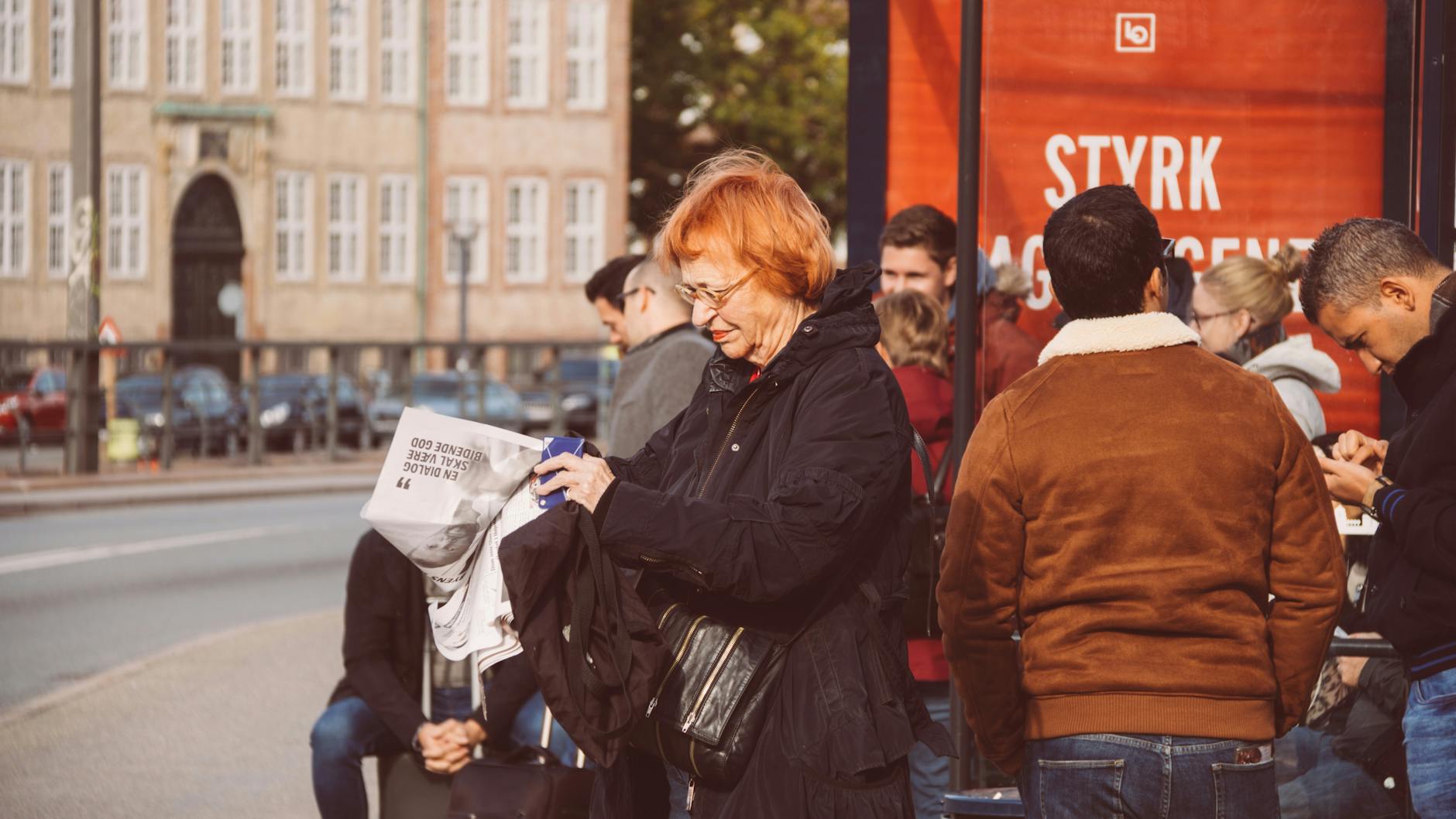 People at a Copenhagen bus stop for journalist departure planning.