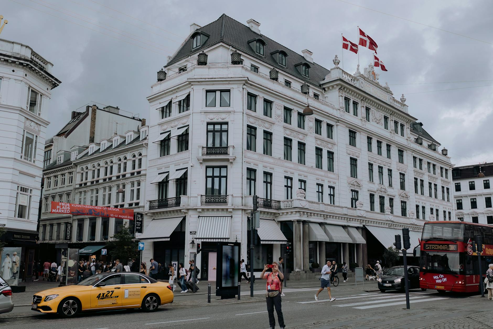 Busy Copenhagen street with Danish flags for tourist lodging planning.