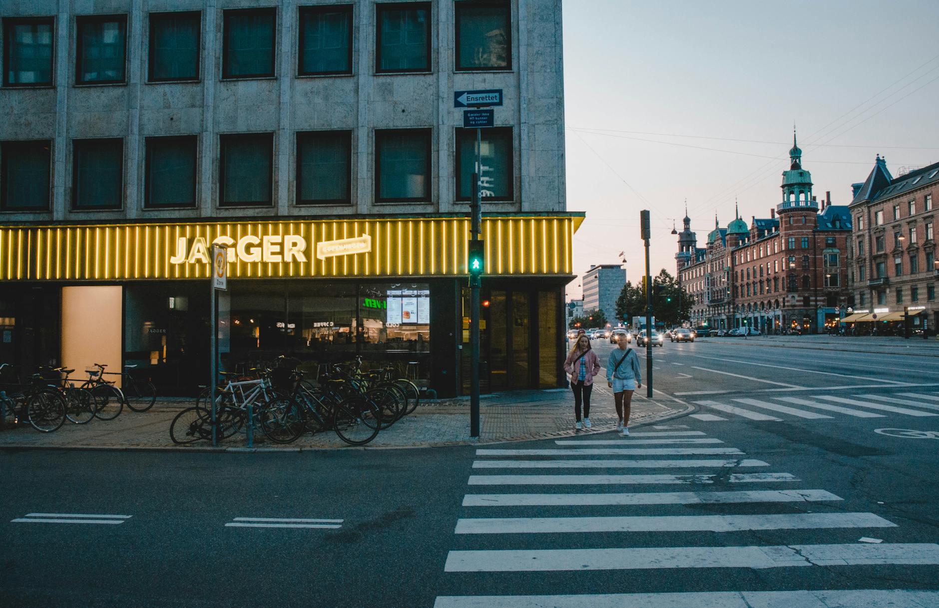 Women walking by bicycles in Copenhagen for lodging and return-route planning.