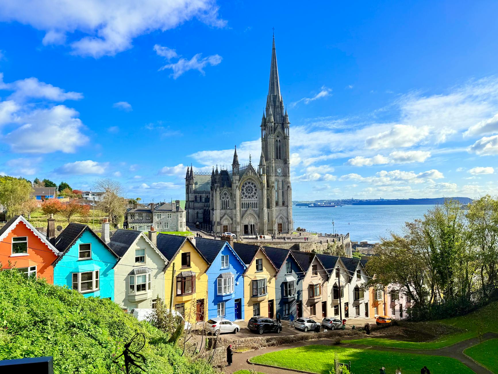 Vibrant colorful houses and cathedral in Cobh, Ireland with Atlantic Ocean backdrop.